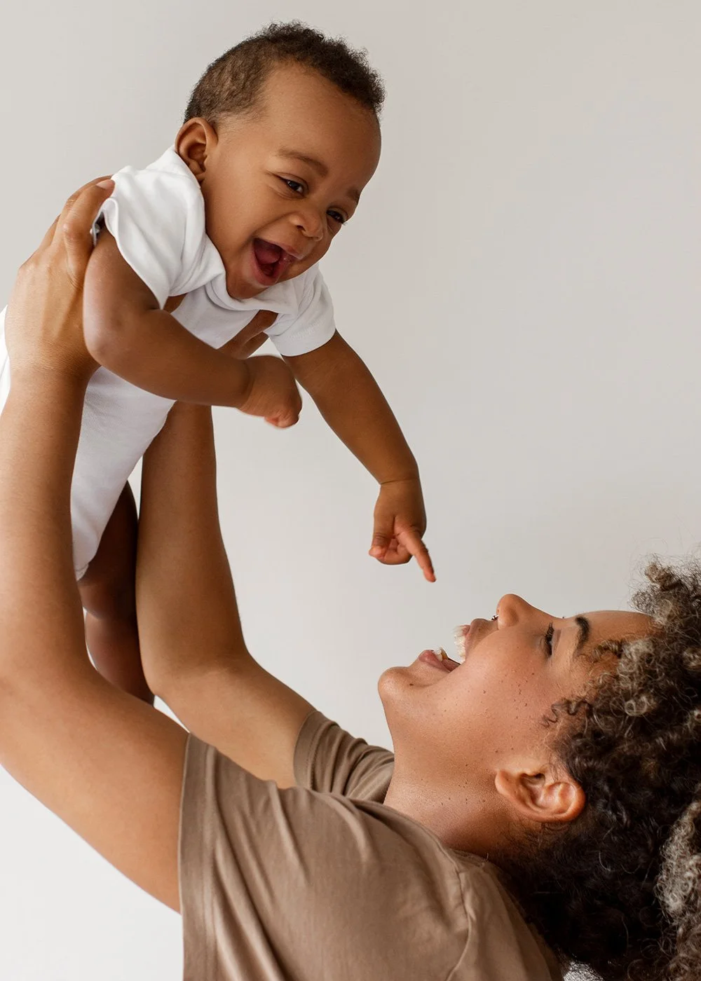 Laughing parent lifting baby playfully into the air