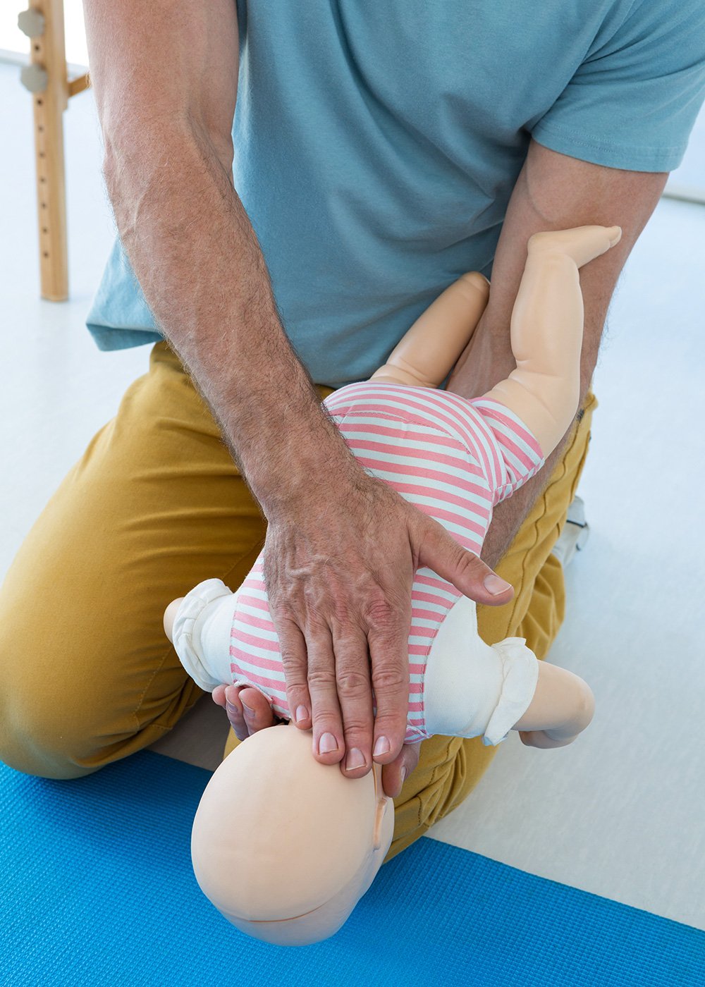 Adult holding a baby manikin while demonstrating infant CPR