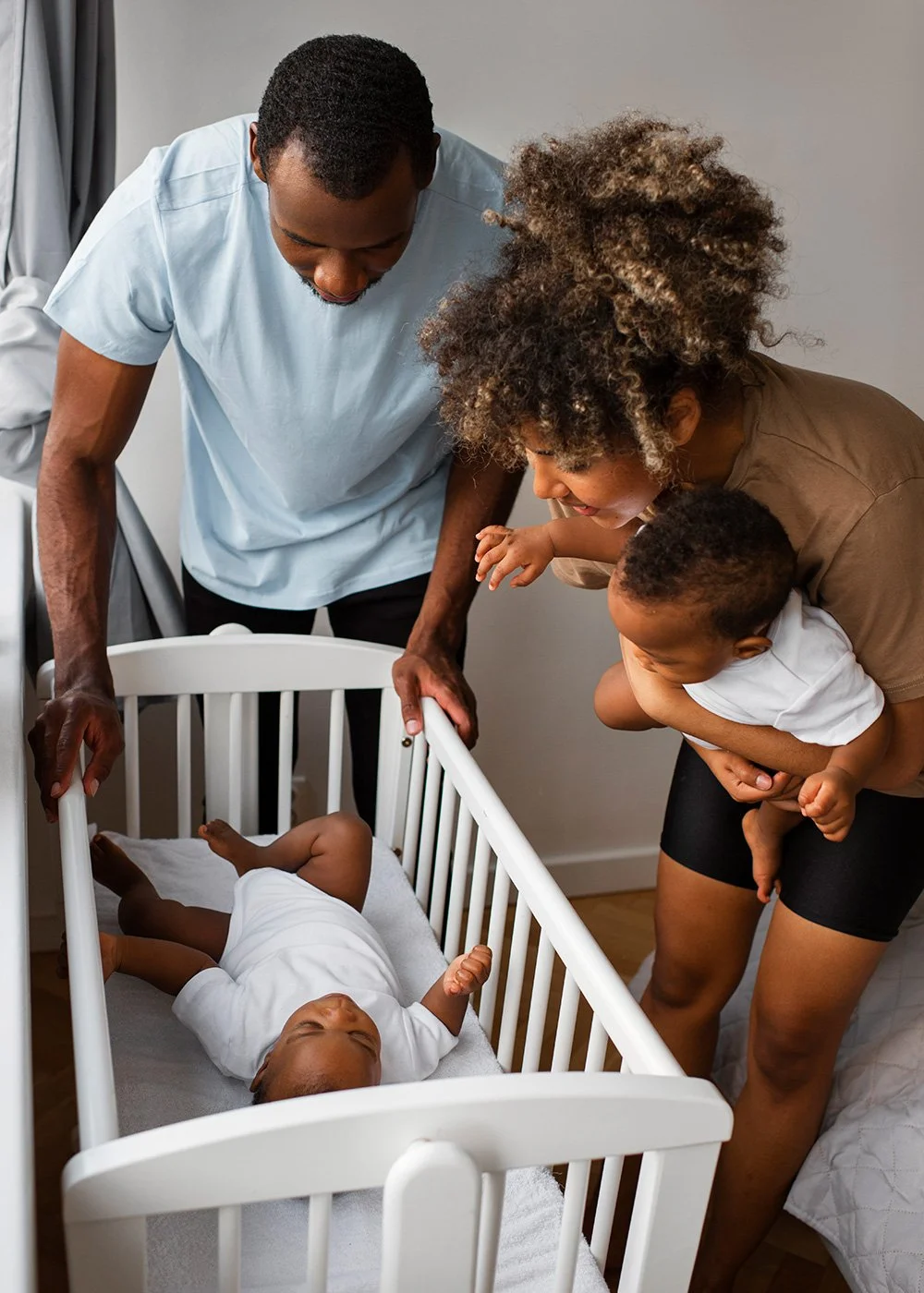 Parents standing by a crib, lovingly interacting with twins
