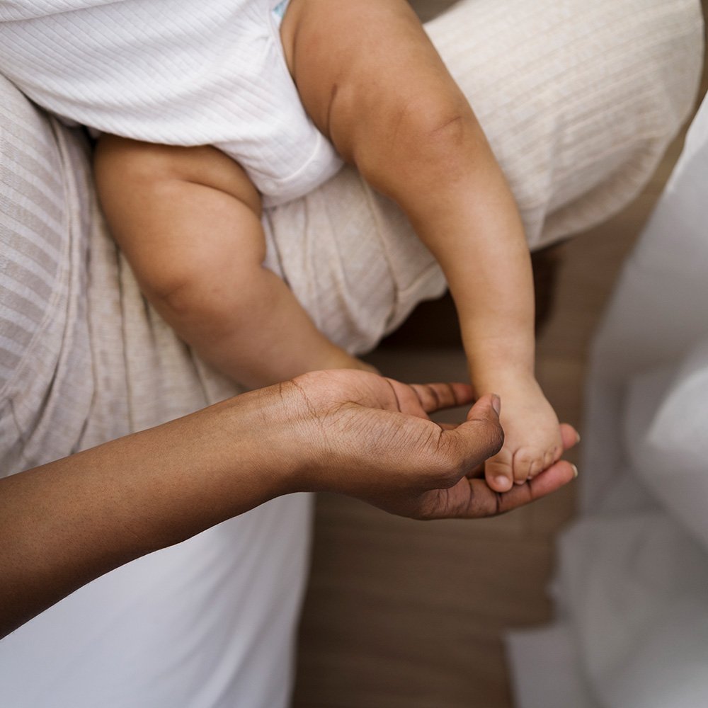 Close-up of a newborn being held by a parent, focusing on gentle hands and skin-to-skin contact