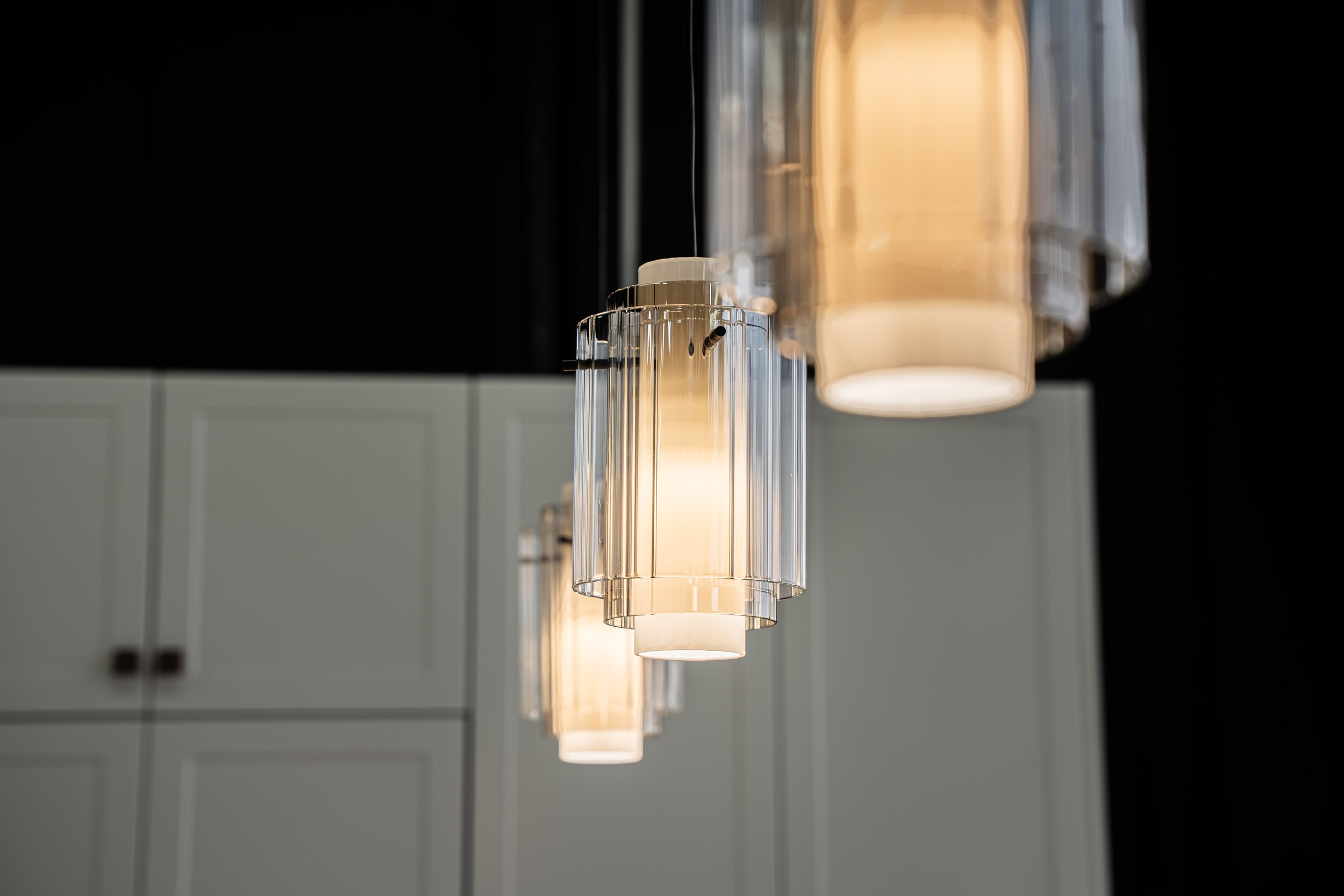 Group of modern pendant lights with clear glass shades hanging from the ceiling in a contemporary interior space.