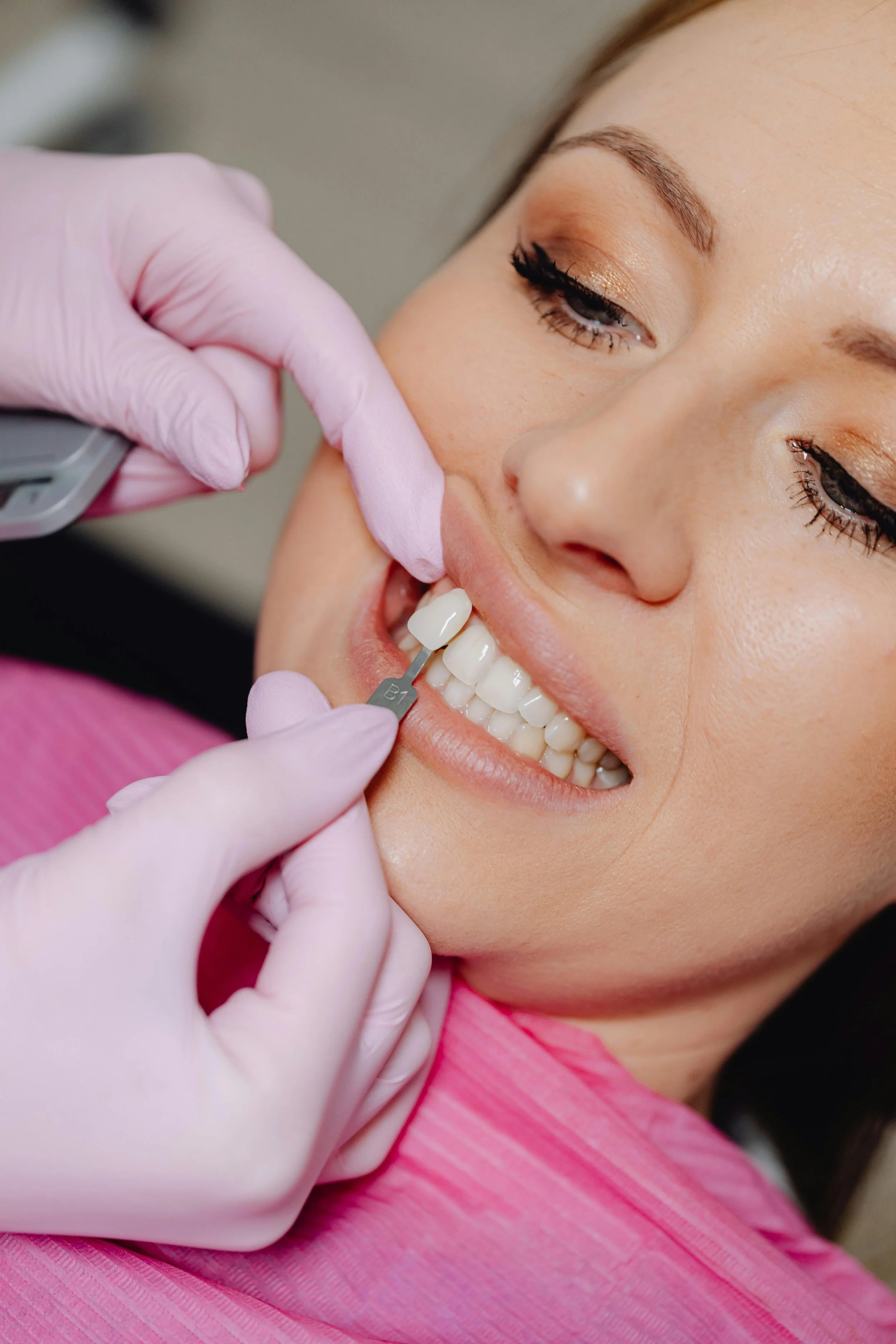 Dentist holding a fake tooth in front of a patient's teeth