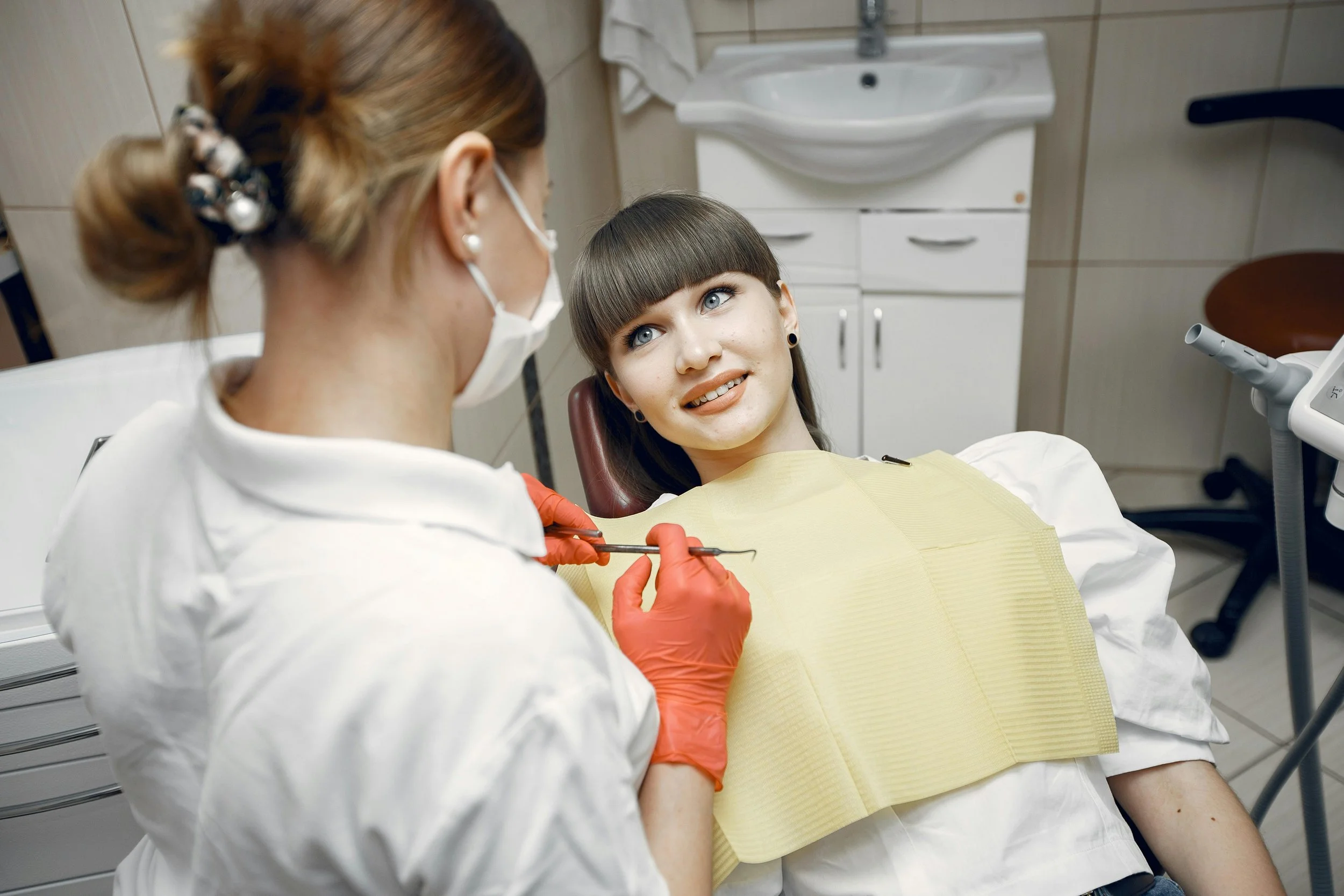 Smiling patient sitting in dental chair during consultation with female dentist wearing gloves