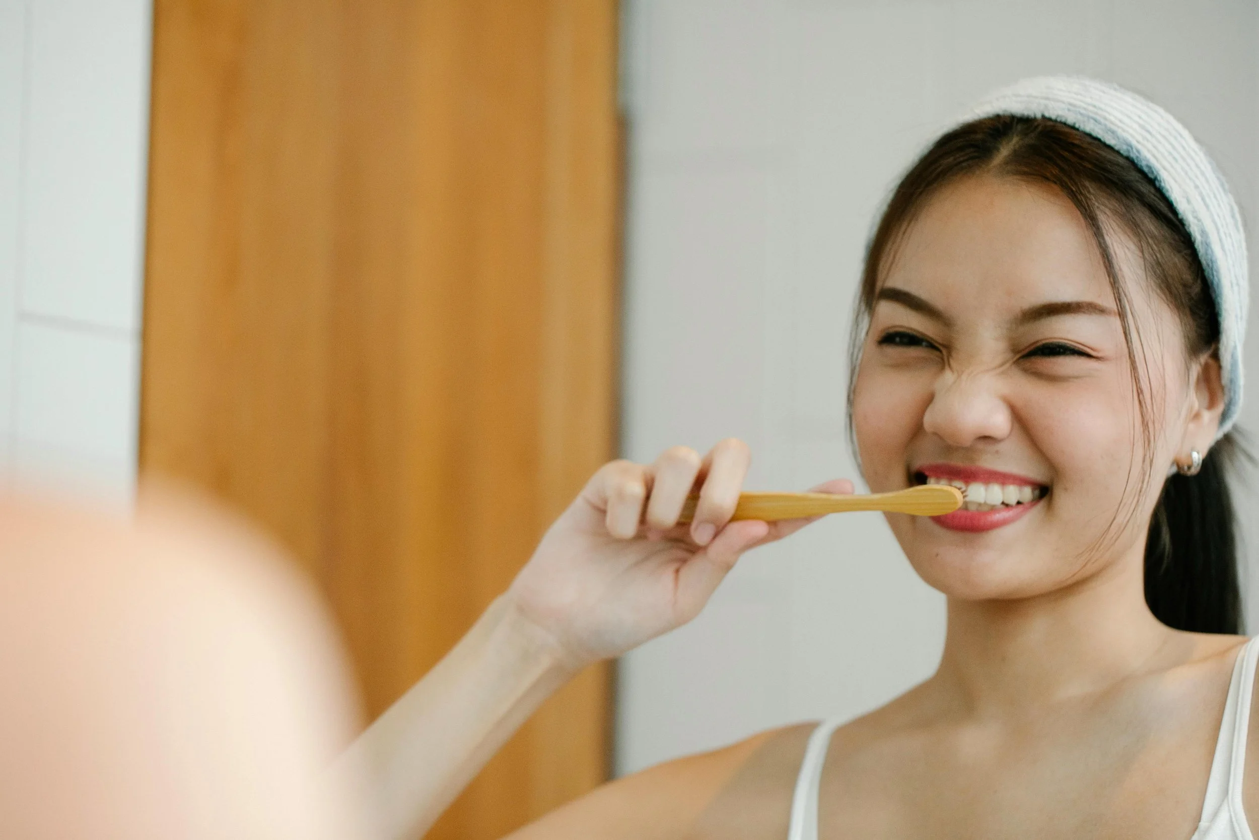 Smiling woman practicing good dental hygiene by brushing teeth at home.