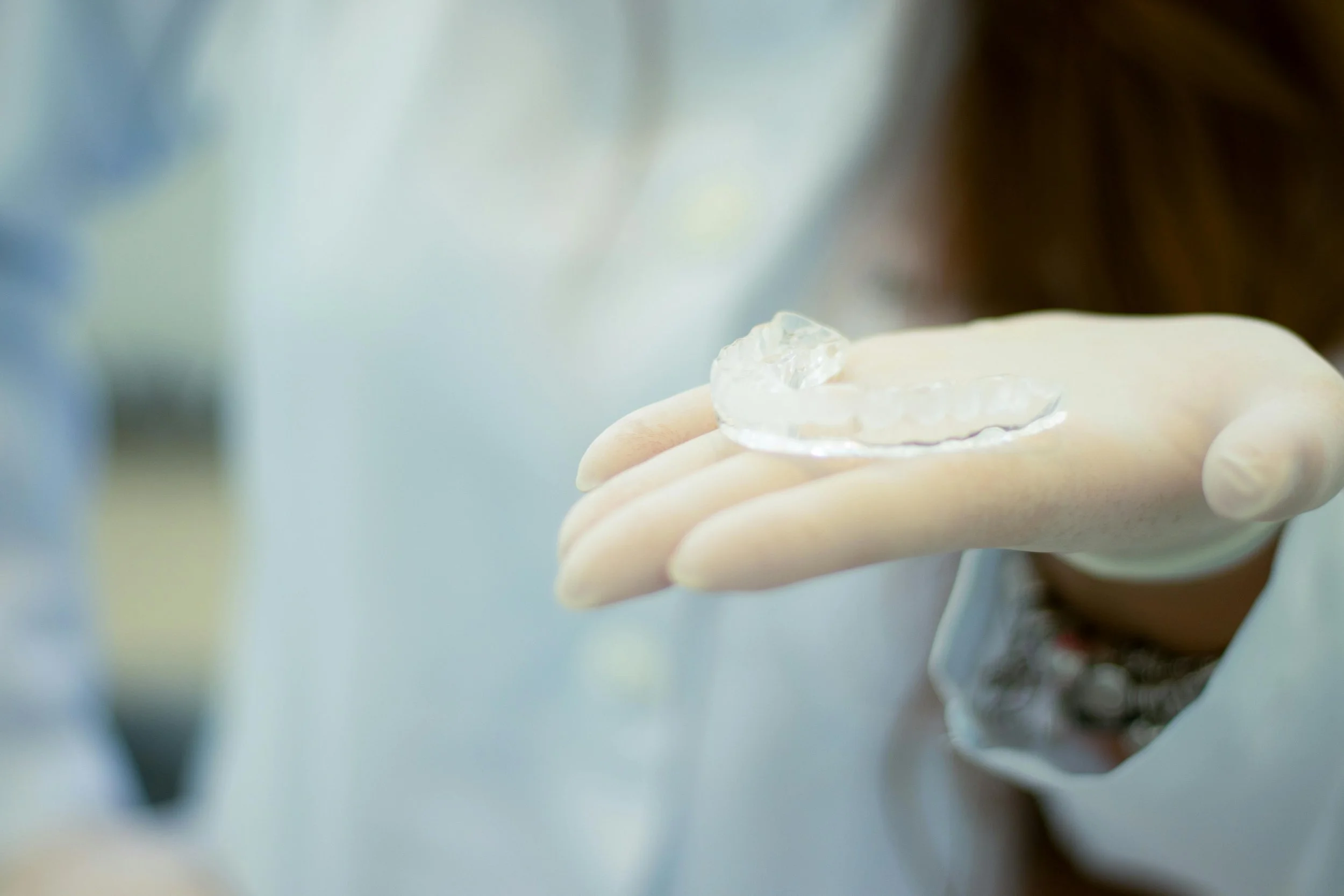 Gloved hand holding a clear mouthguard