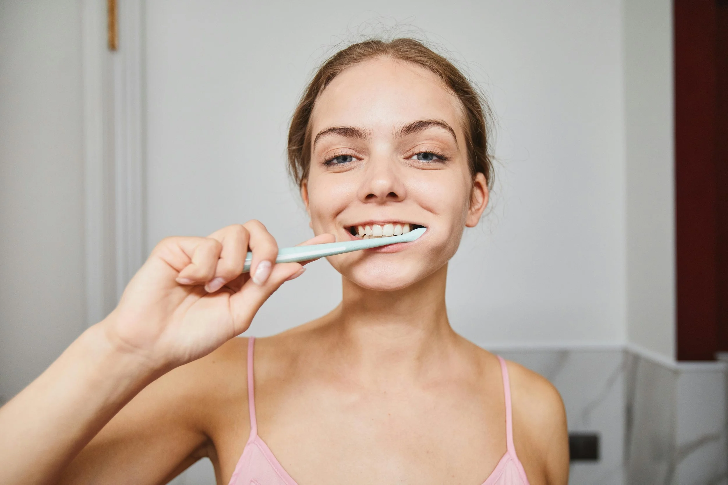 Woman smiling while brushing her teeth