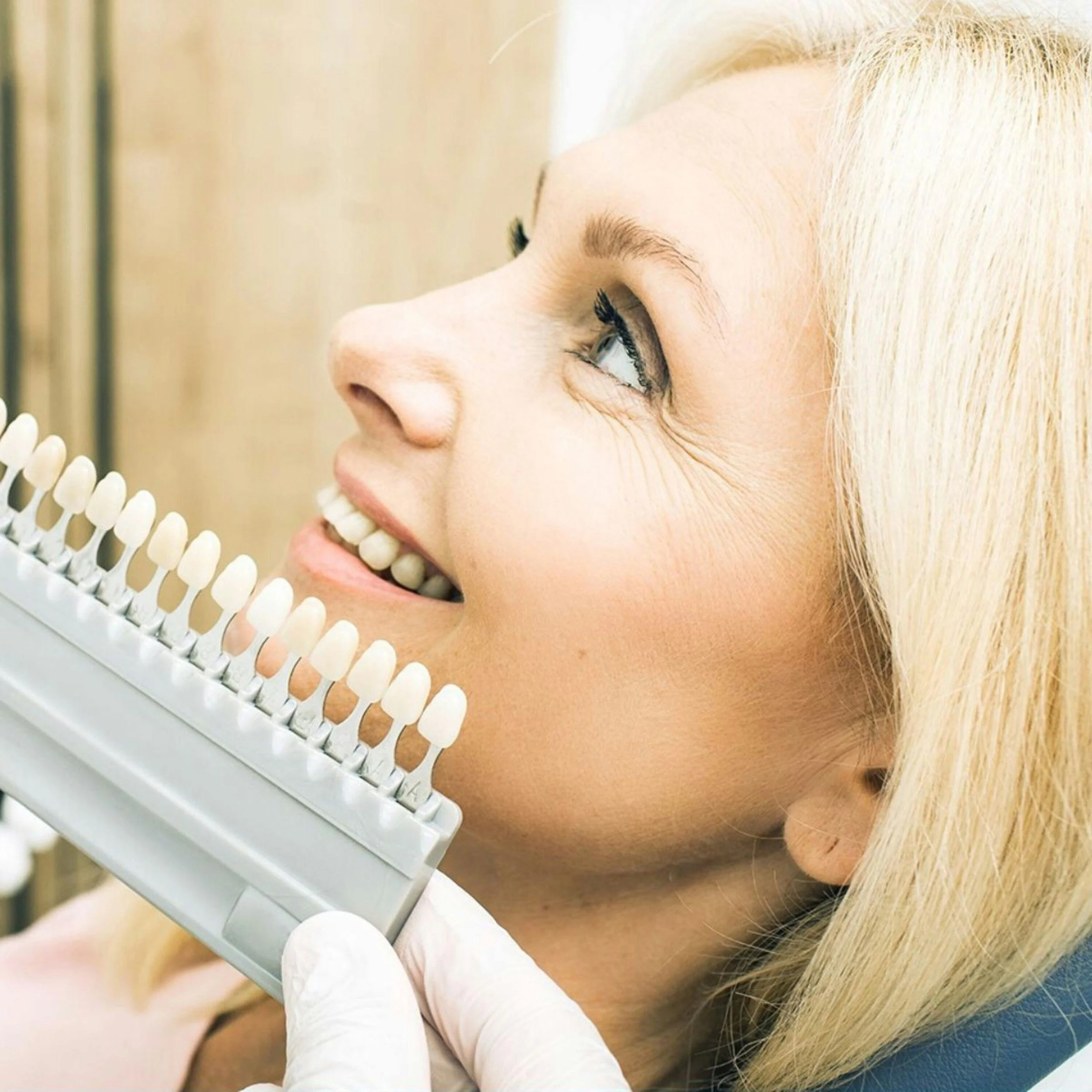 A woman comparing tooth colour using a colour chart