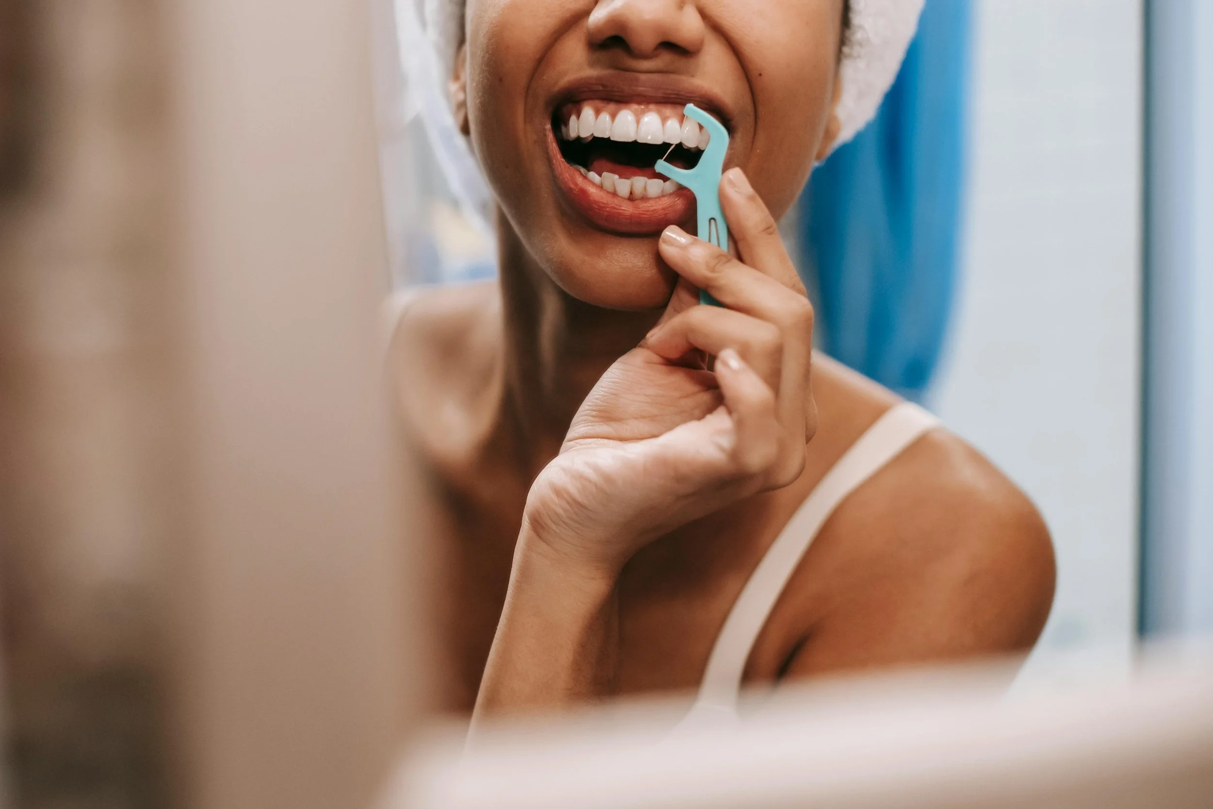 Close up of a woman flossing her teeth in a mirror