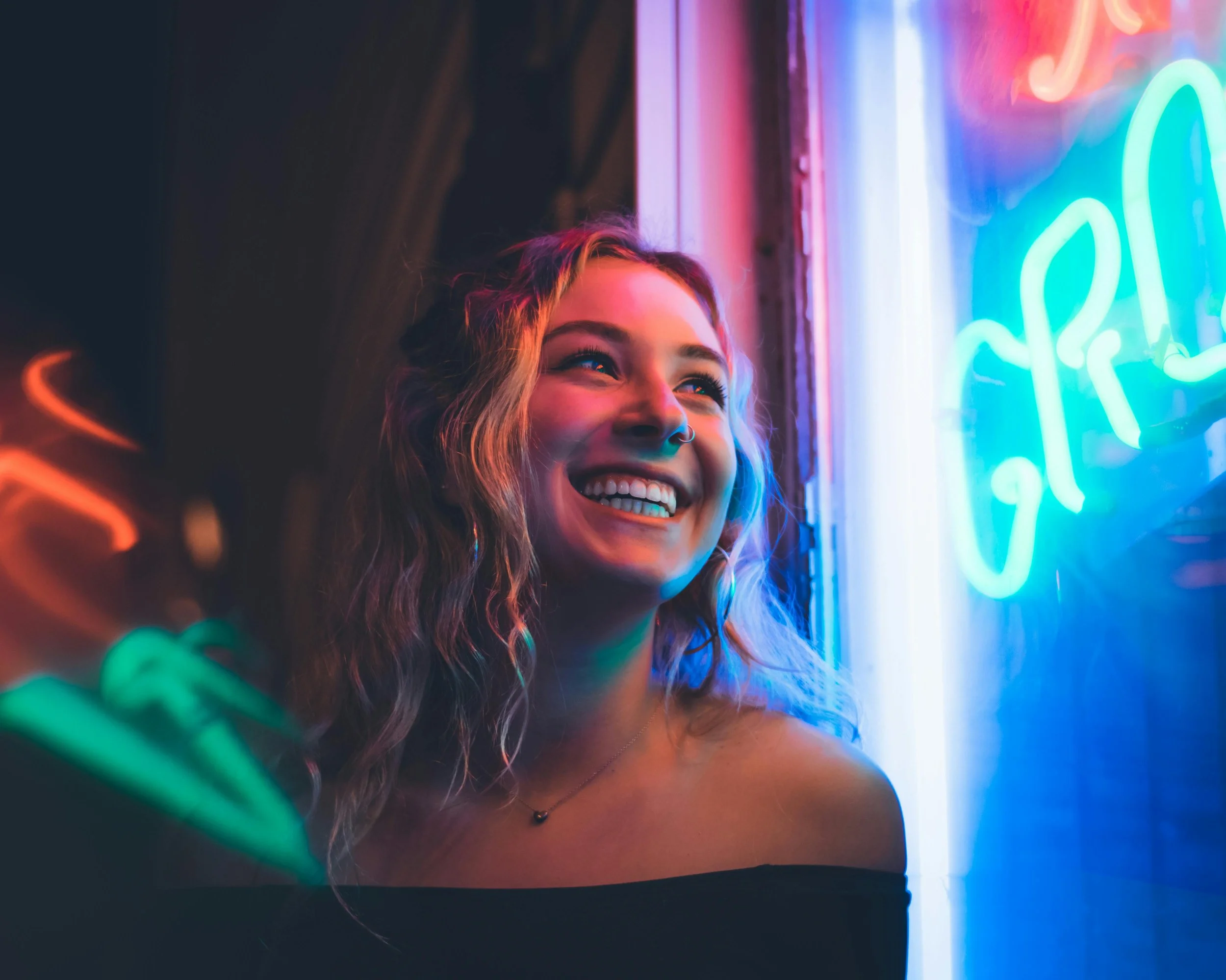 Smiling woman in front of a neon sign