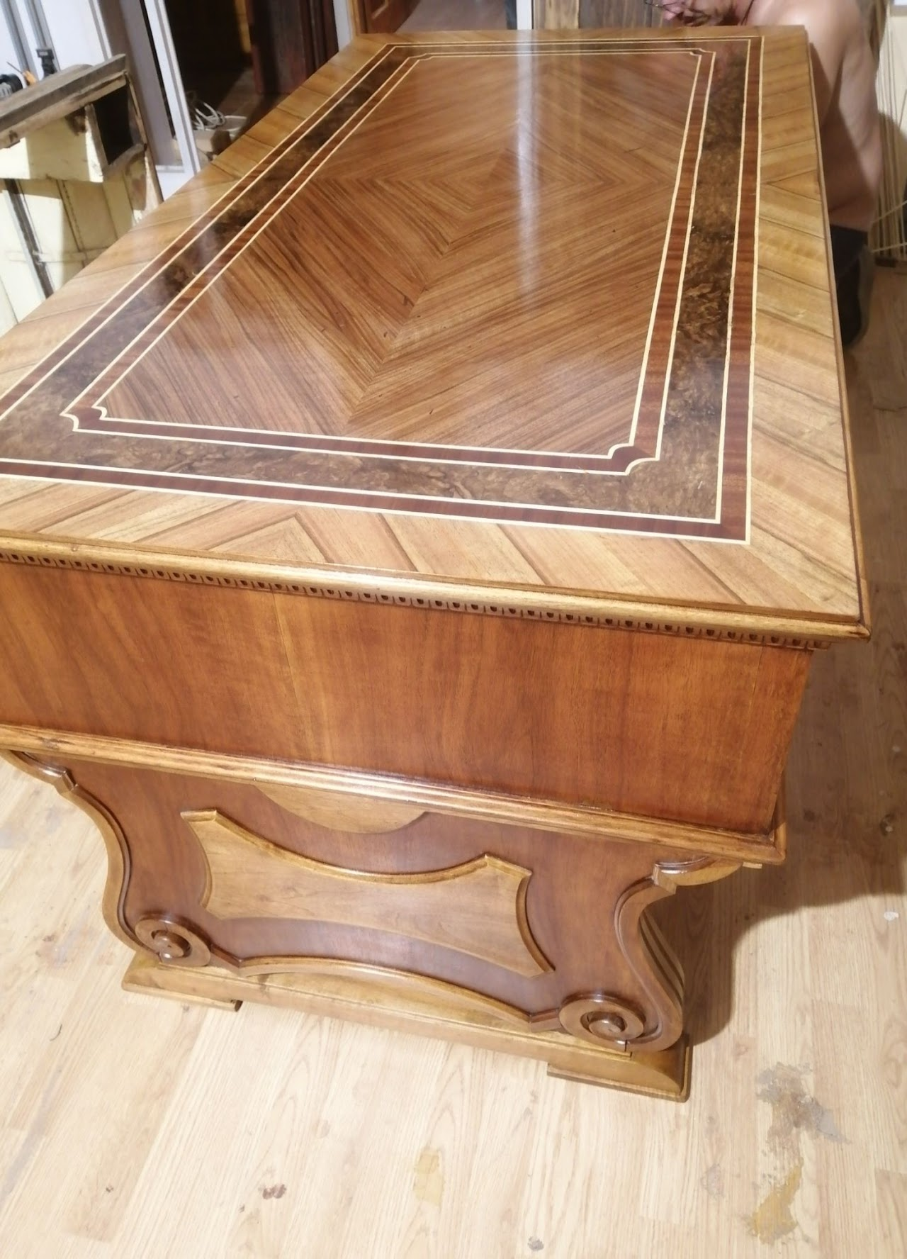 Elegant wooden table with inlaid decorative design on the surface, featuring a top with geometric patterns and a carved base.