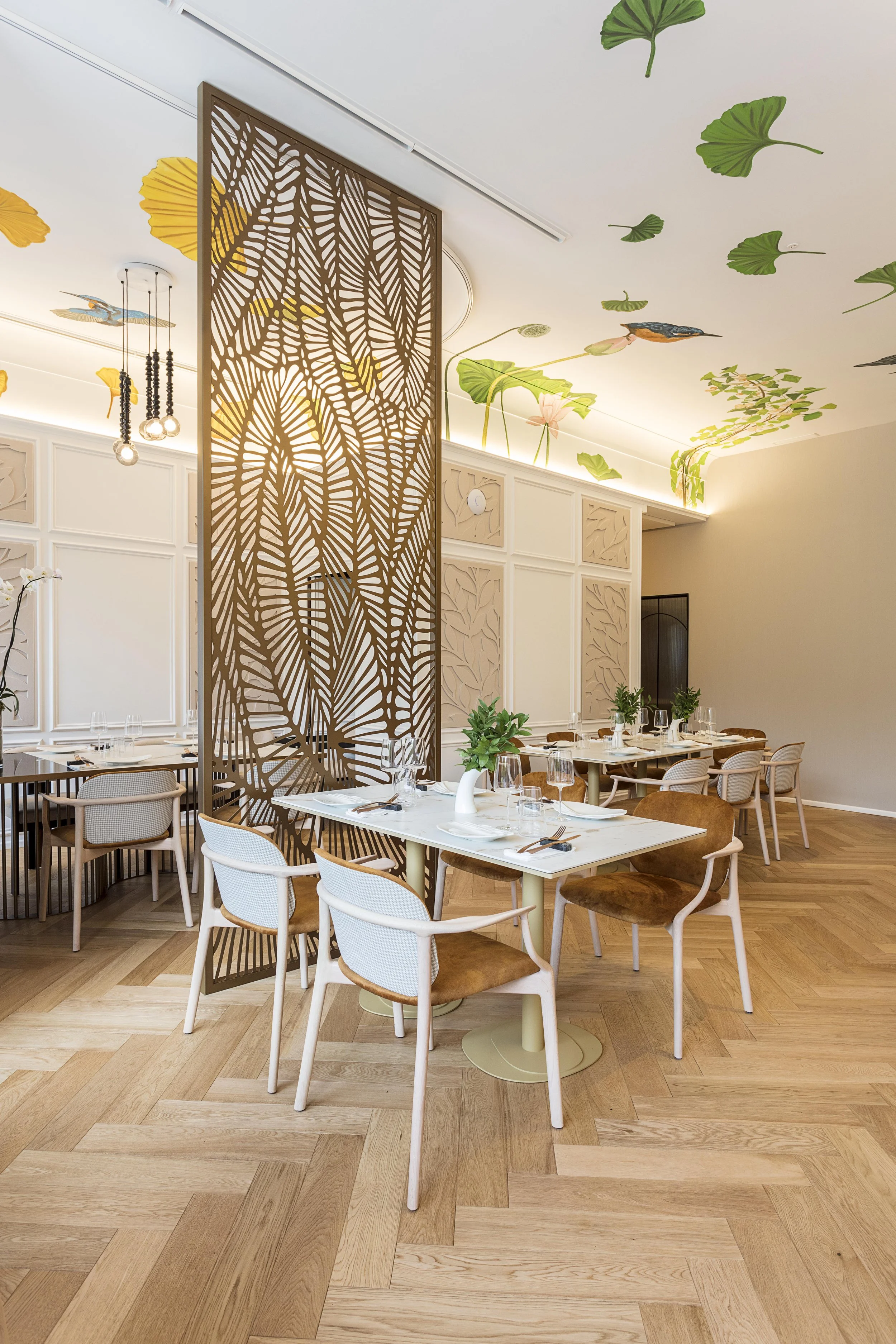 Empty wooden dining chair in a modern restaurant with a table set with glasses and plates in the background.