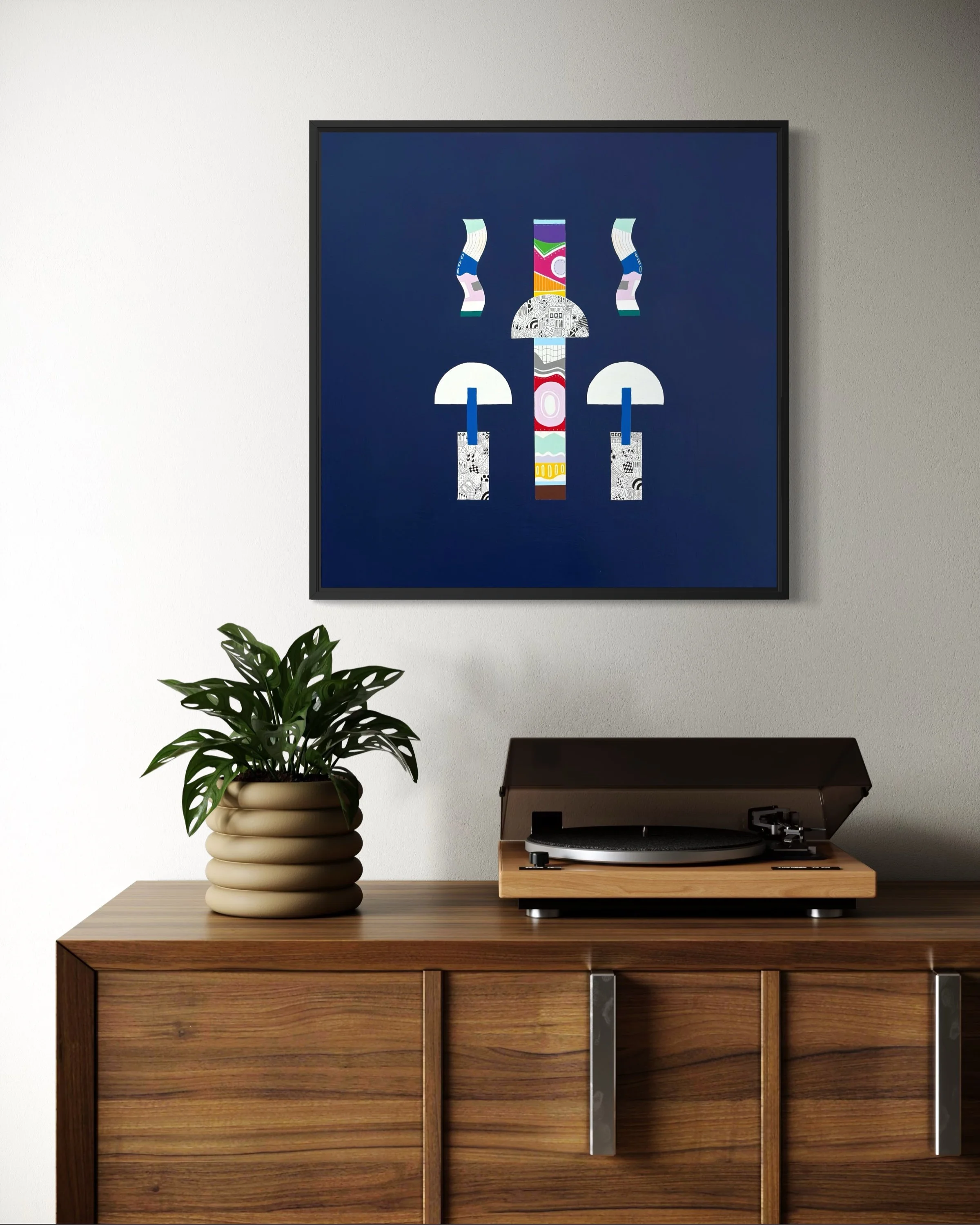 Mostly In Place, original mixed media abstract on canvas with a dark blue background, framed in black and displayed on a light coloured wall above a record player.