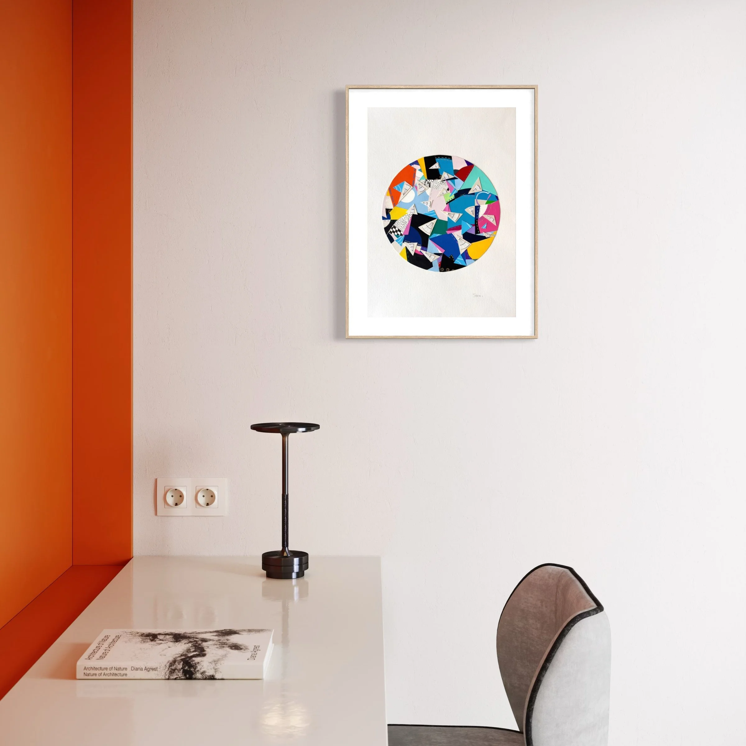 A Restless Centre, A3 abstract mixed media collage with a circular centre of coloured fragments and triangular pen drawings displayed framed above a desk.