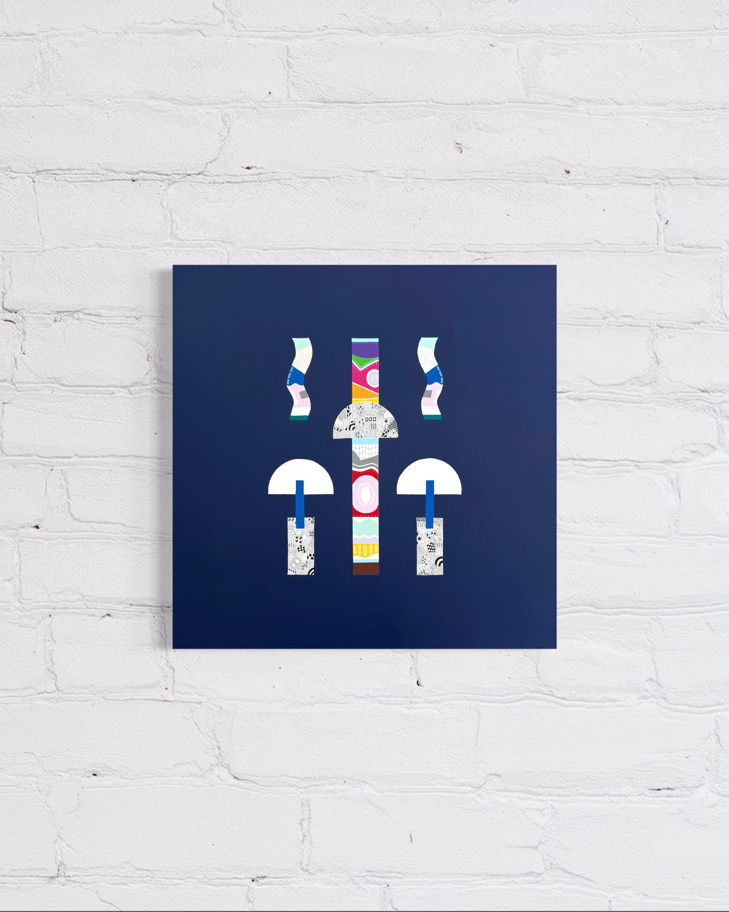 Two, original mixed media abstract on canvas with a blue background, displayed on a white brick wall.