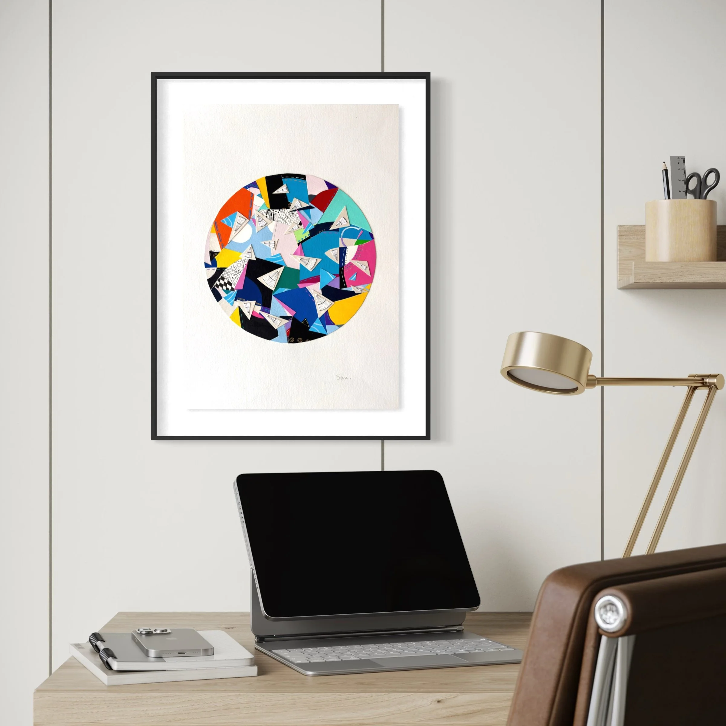 A Restless Centre, A3 abstract mixed media collage with a circular centre of coloured fragments and triangular pen drawings displayed framed above a desk.