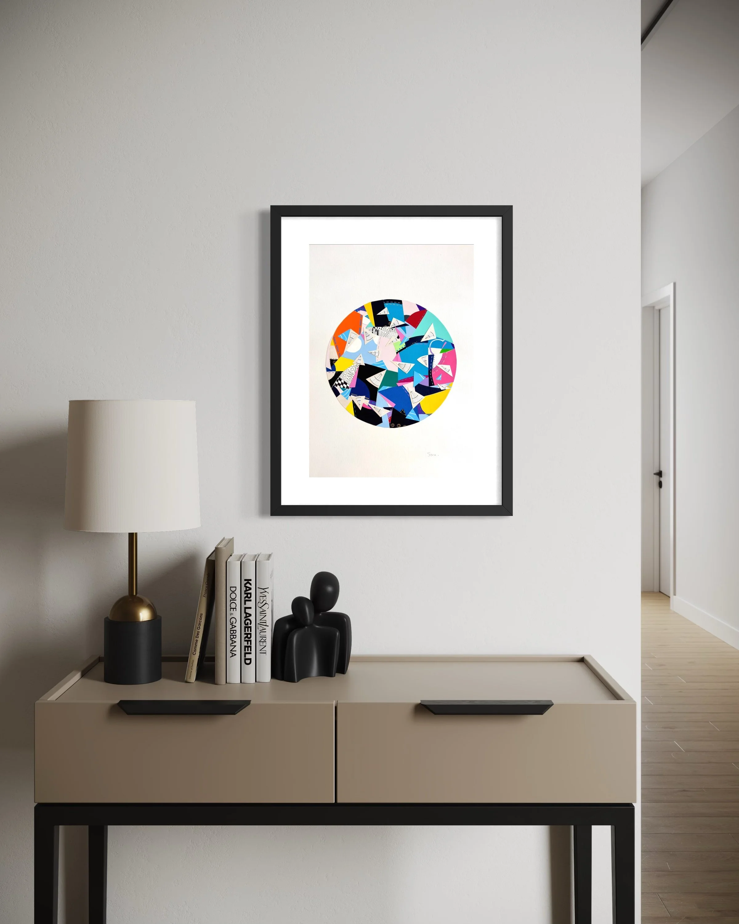 A Restless Centre, A3 abstract mixed media collage with a circular centre of coloured fragments and triangular pen drawings displayed framed above a hallway table.