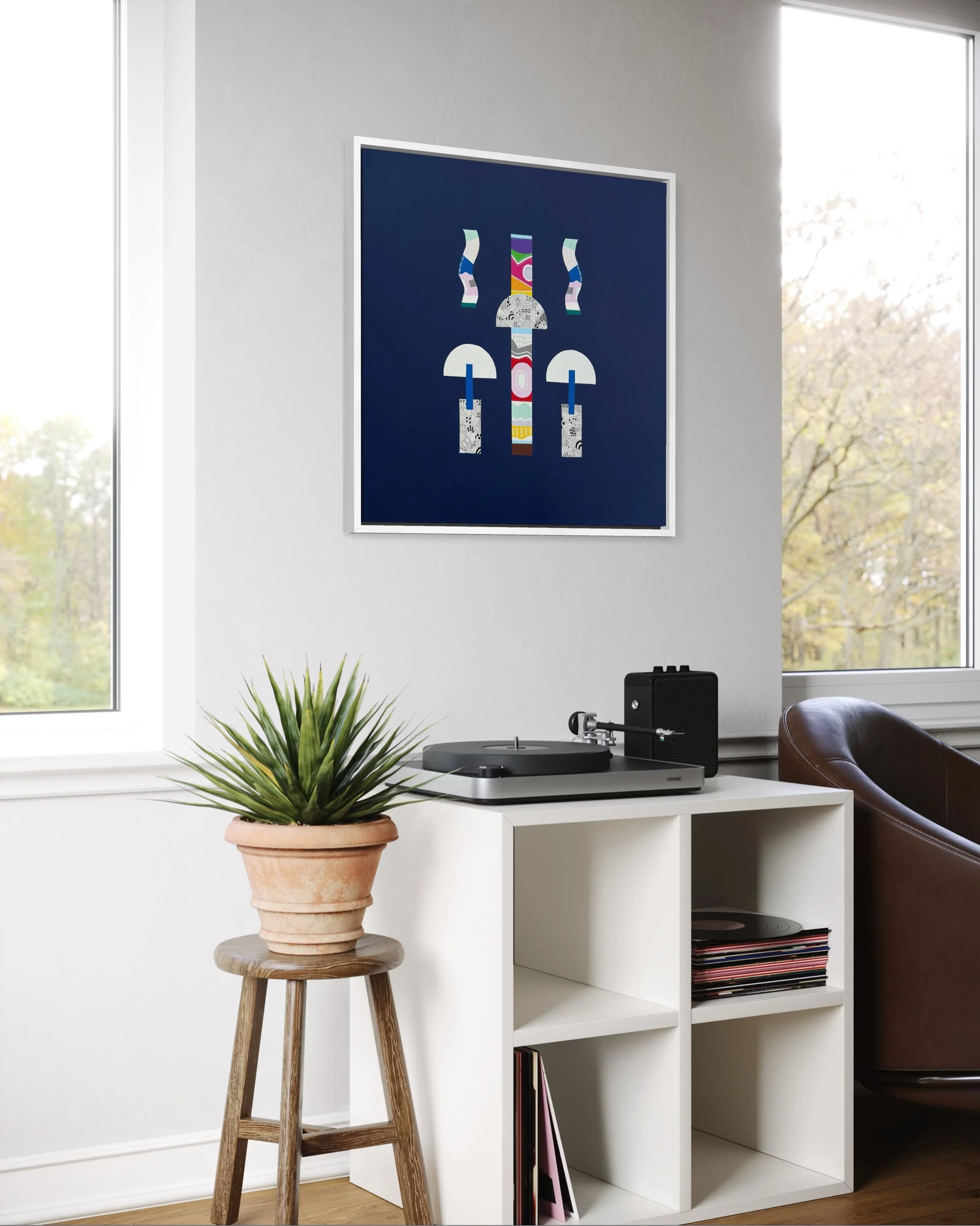 Mostly In Place, original mixed media abstract on canvas with a dark blue background, displayed with a white fram in a modern living room on a white wall above some shelves.