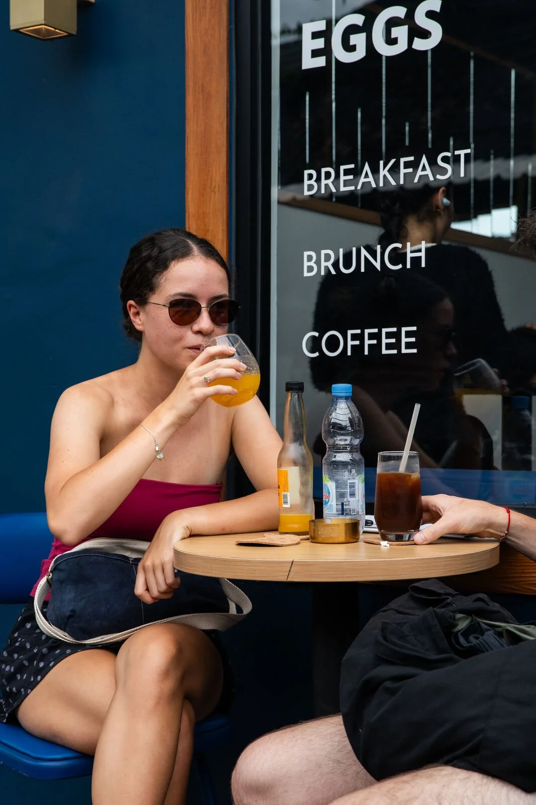 Guests enjoying drinks outside Studio Egg cafe in Ubud Bali — iced coffee and kombucha with Eggs Breakfast Brunch Coffee signage in background