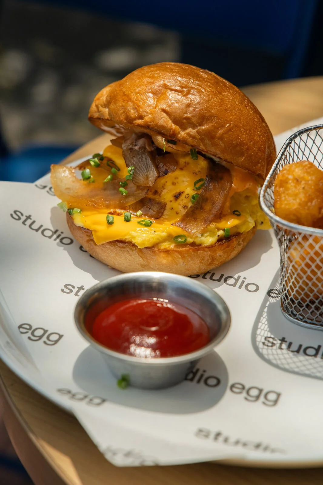 The Egg Sandwich at Studio Egg Ubud Bali — soft scrambled cage-free eggs, sharp cheddar, caramelised onion and chives on brioche bun served with tater tots