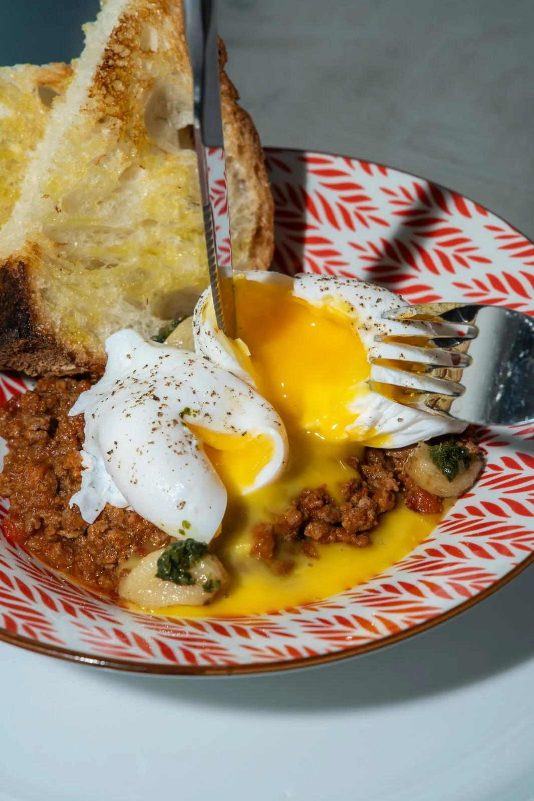 Lamb Shakshouka at Studio Egg Ubud Bali — poached cage-free eggs with minced lamb, green zhoug and garlic confit served with ancient grain sourdough