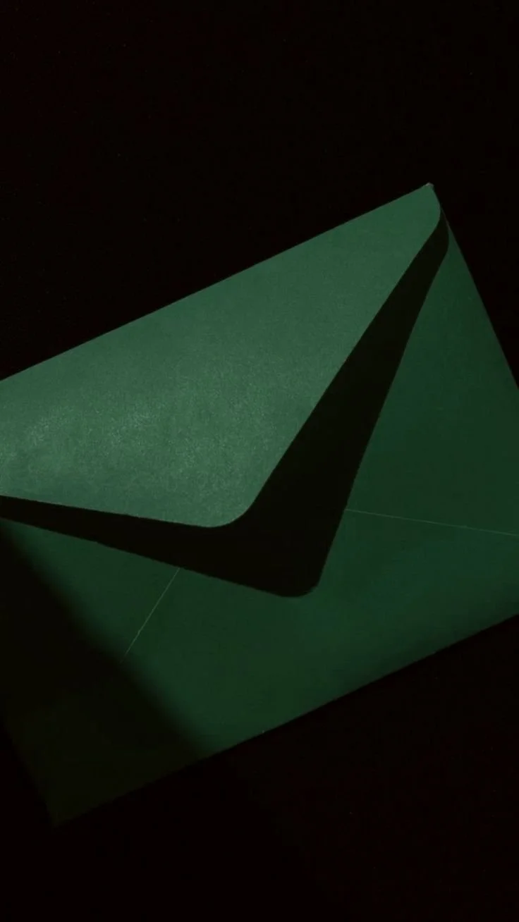 A dark green paper airplane against a black background.