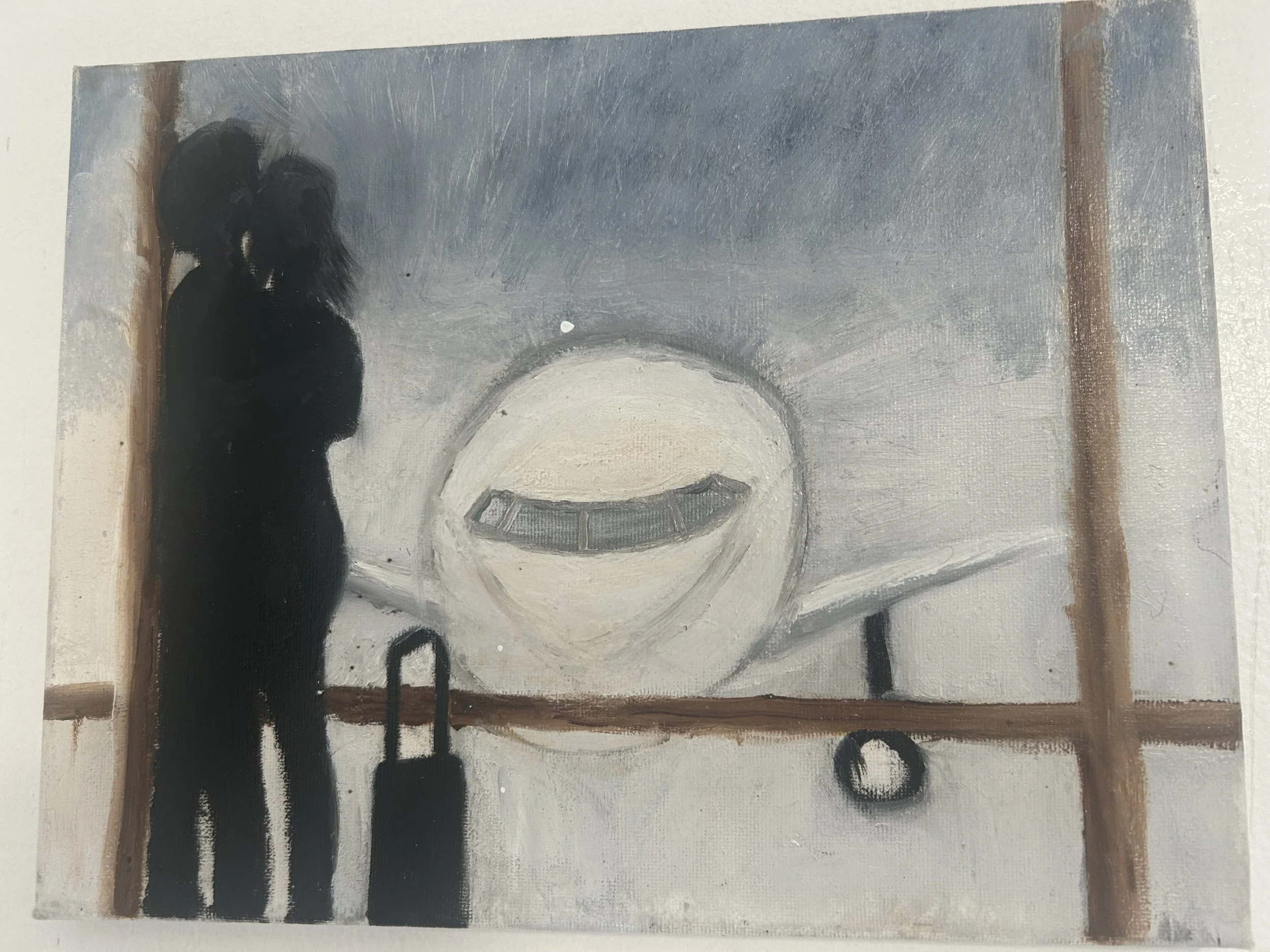 A silhouette of a woman standing at an airport terminal window, looking at an airplane outside. The woman is holding a small rolling suitcase.