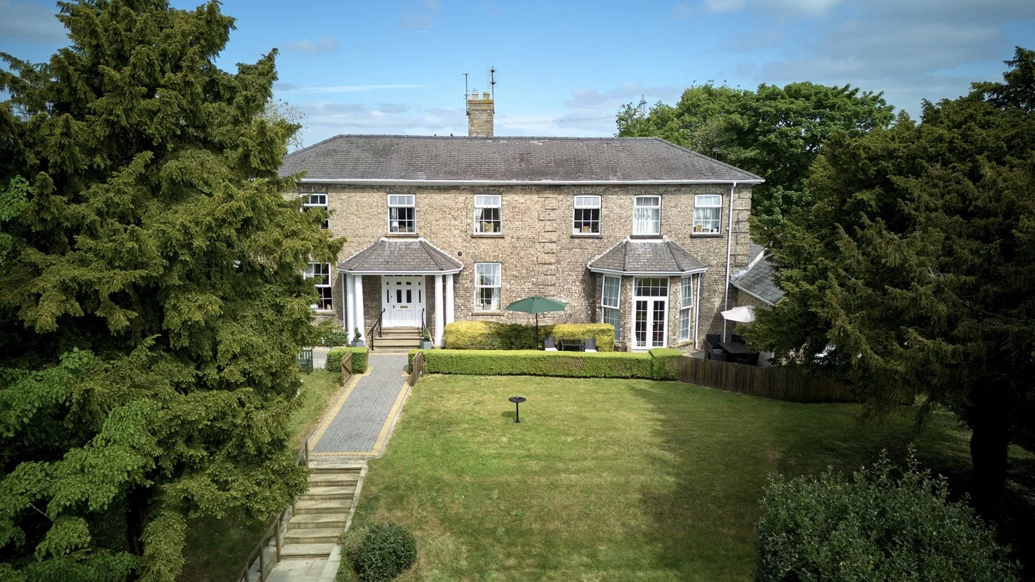 Large brick house with a manicured lawn and trees in the yard.