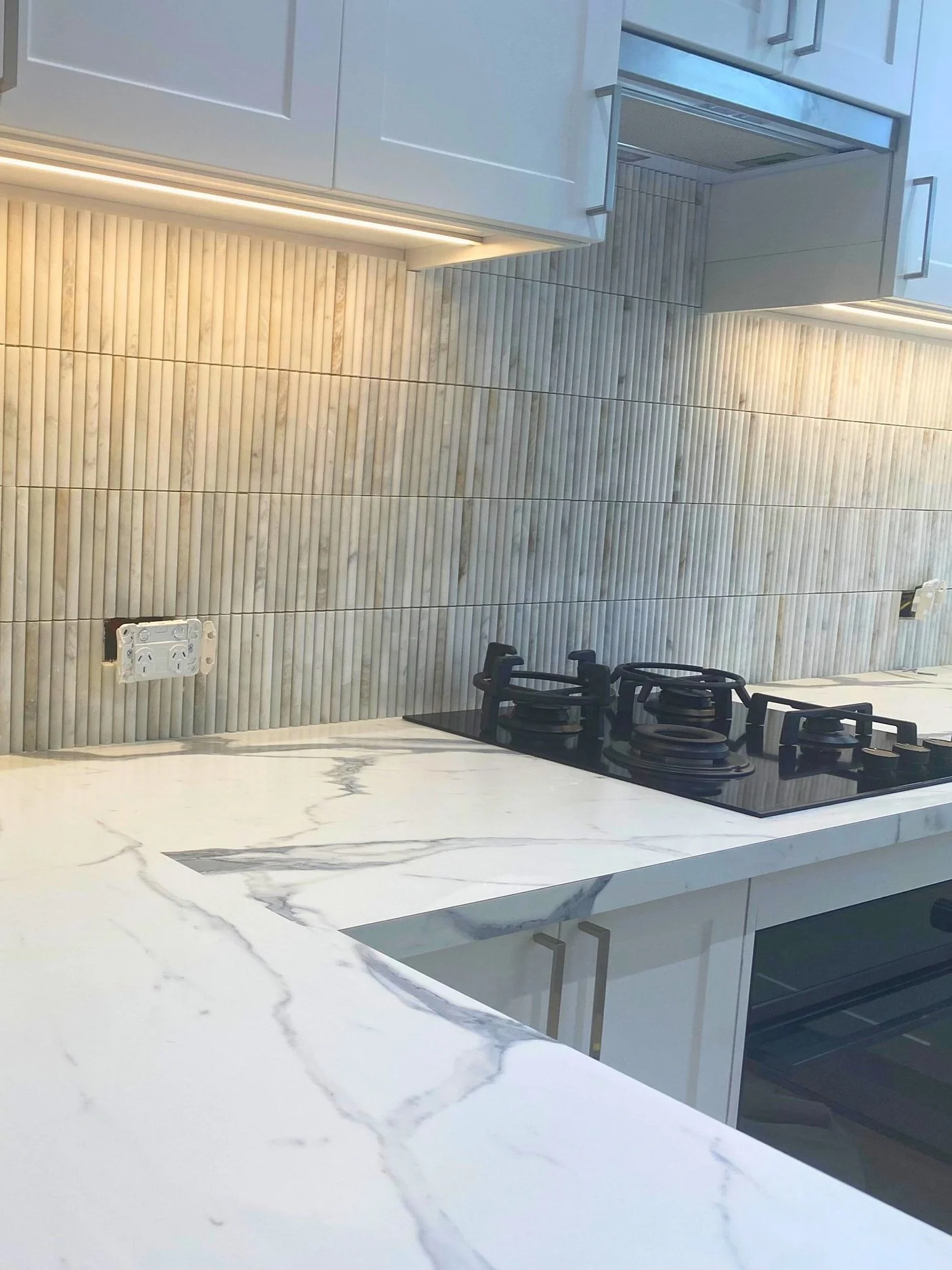 Modern kitchen countertop and backsplash with a gas stove and cabinetry.