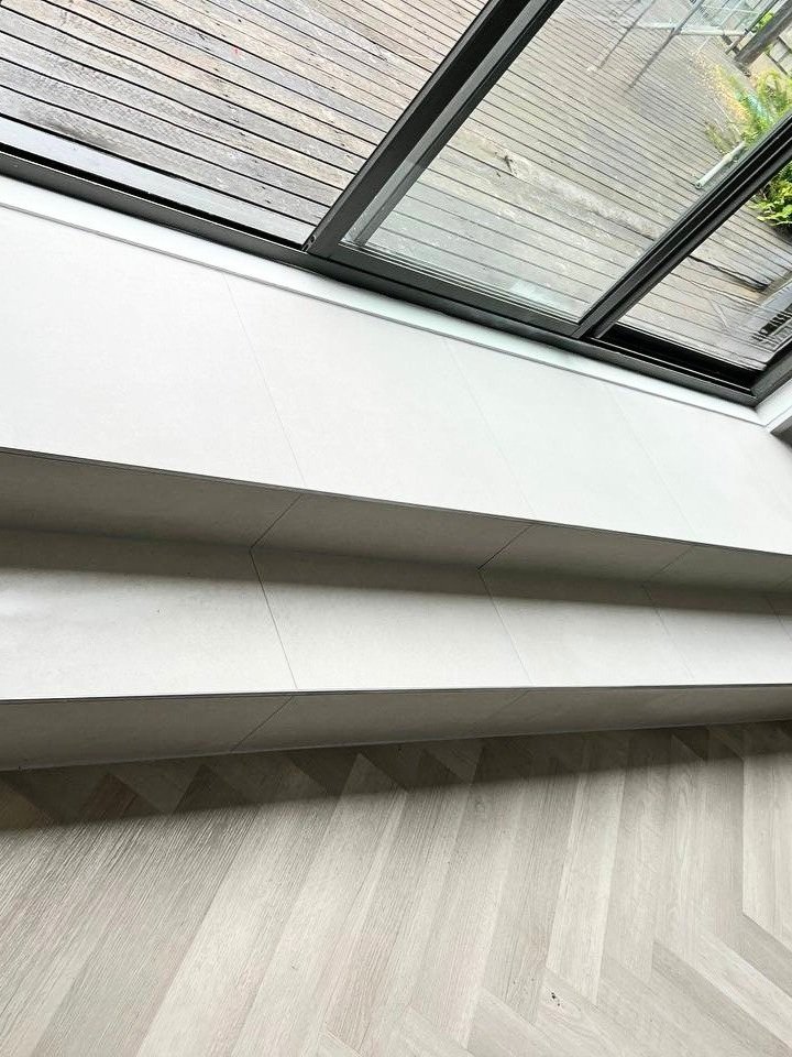 Close-up view of a white window ledge and a sliding glass door opening to a wooden deck outside.