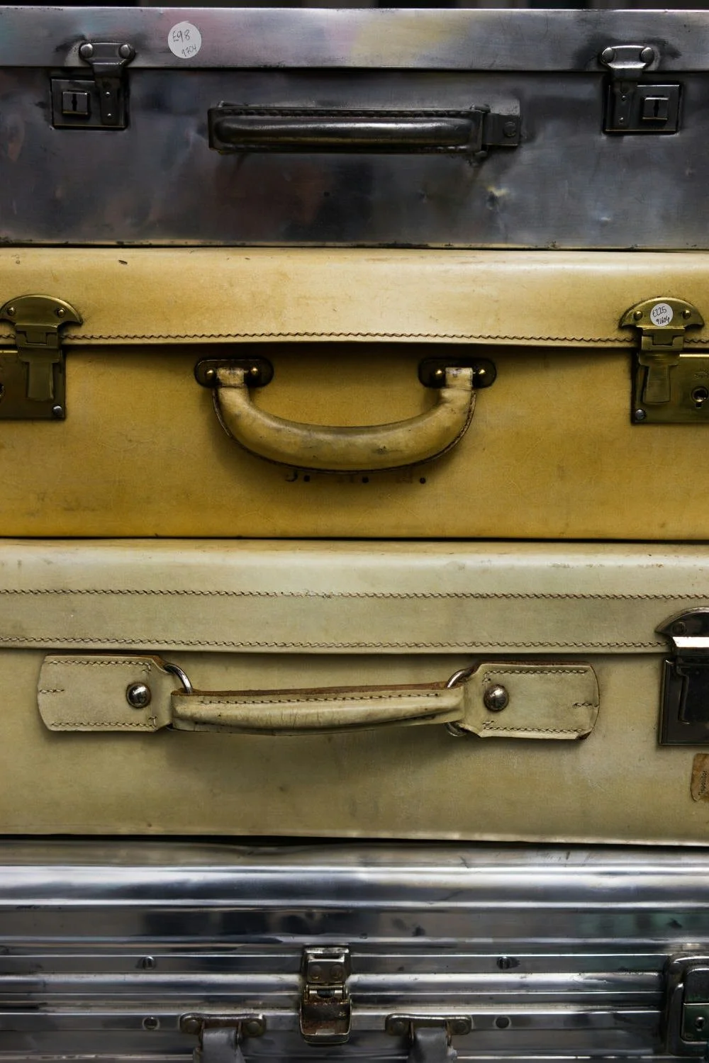 Stacked vintage metal and leather suitcases, with visible handles and latches.