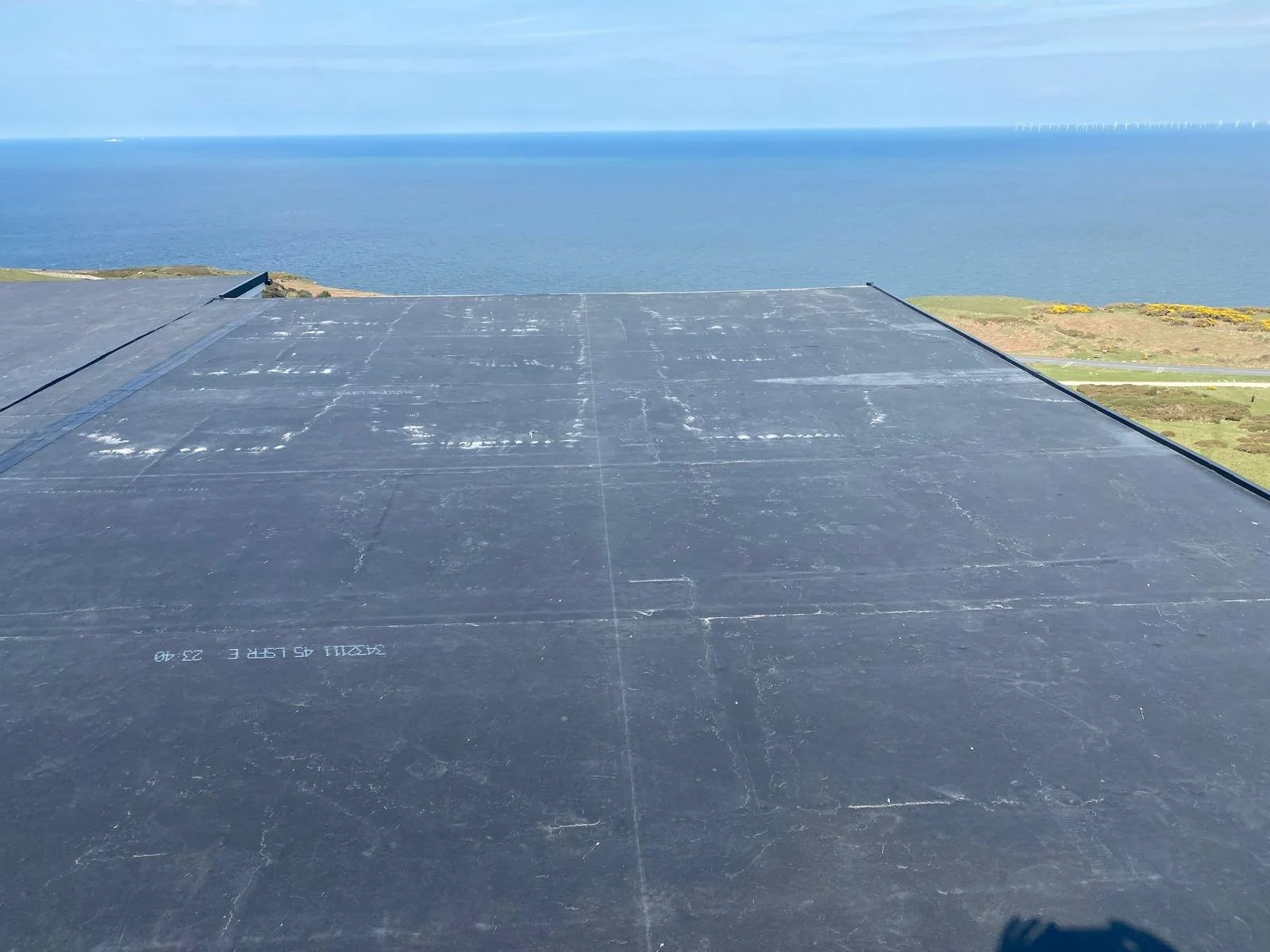 Large flat black solar panel overlooking ocean and coastline.