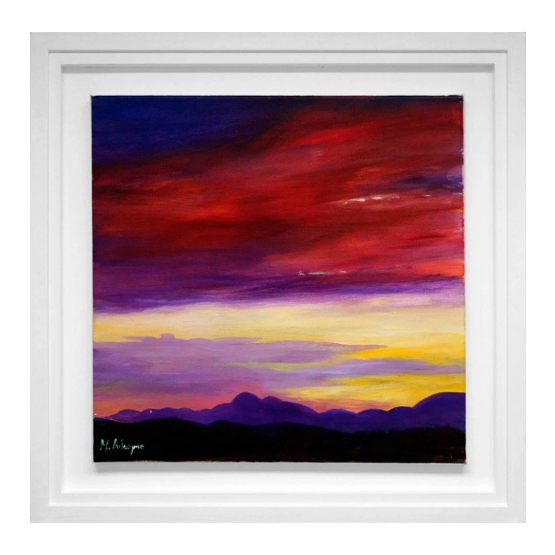 A landscape painting of a sunset with purple, red, yellow, and orange clouds over silhouette mountains, framed in white.