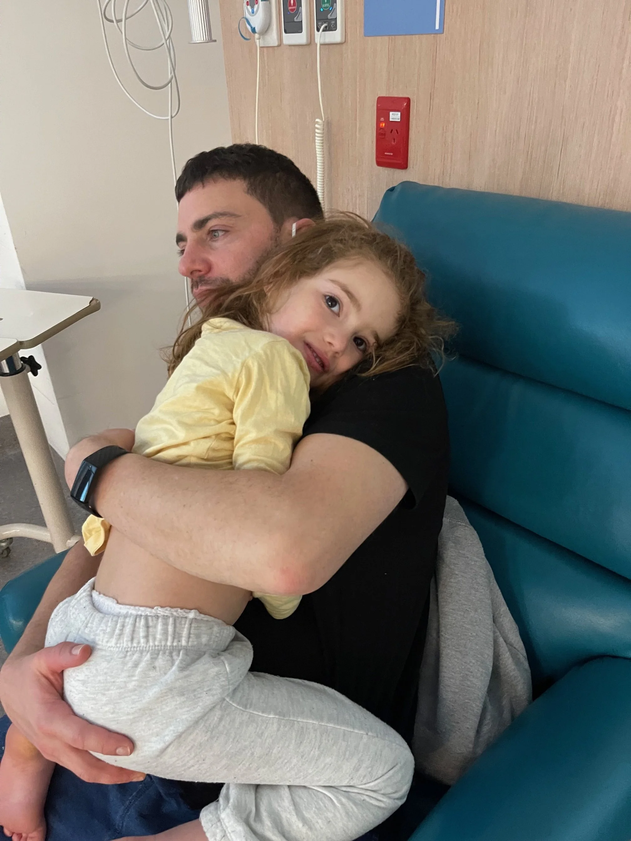 Sasha in the arms of her father being comforted after experiencing seizures from SLC6A1.