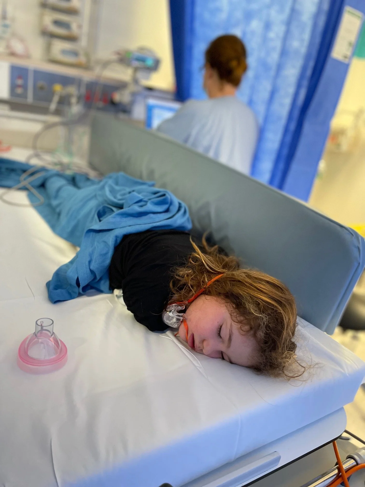 Sasha Lipworth with breathing mask lying on a hospital bed