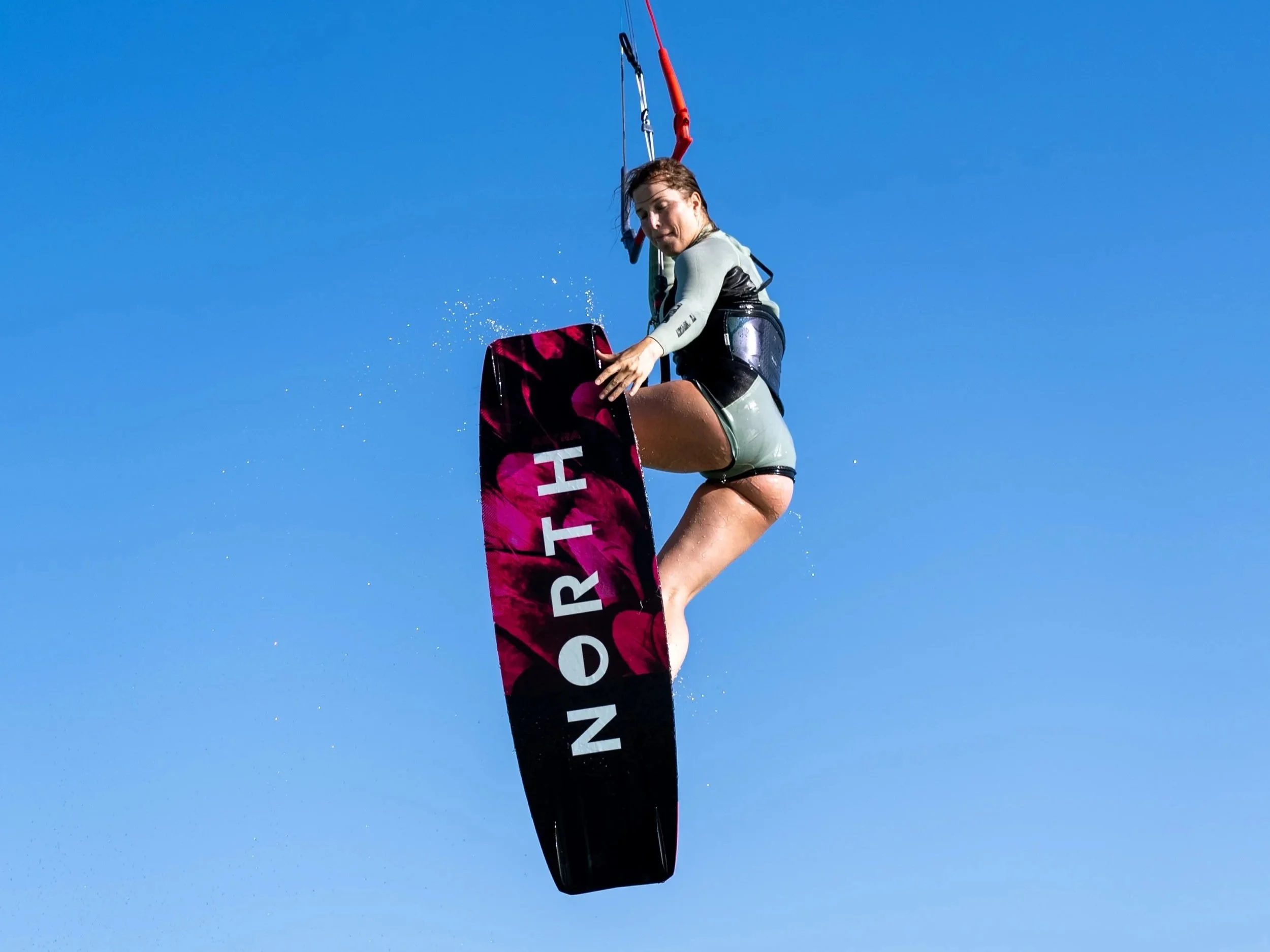 Kite Woman jumping and grabbing her kiteboard