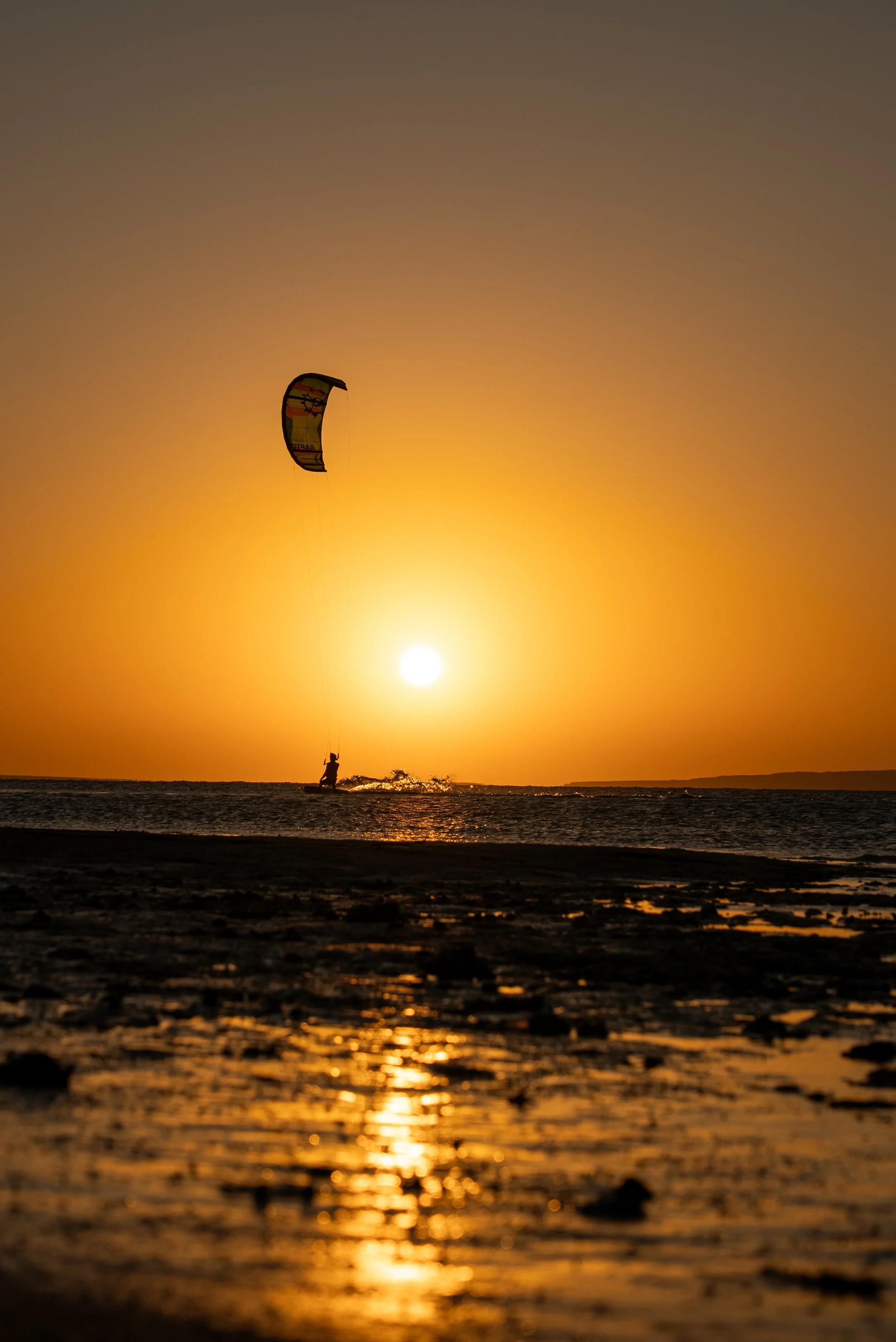 Kitesurfer riding at sunset
