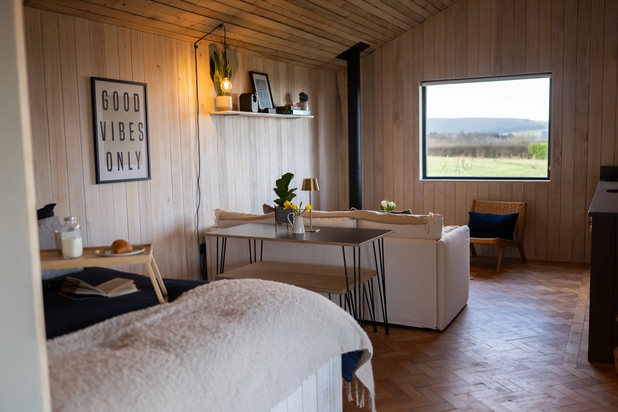 Open plan area of Lir View - bed, sofa and Woodburner along with kitchen area.