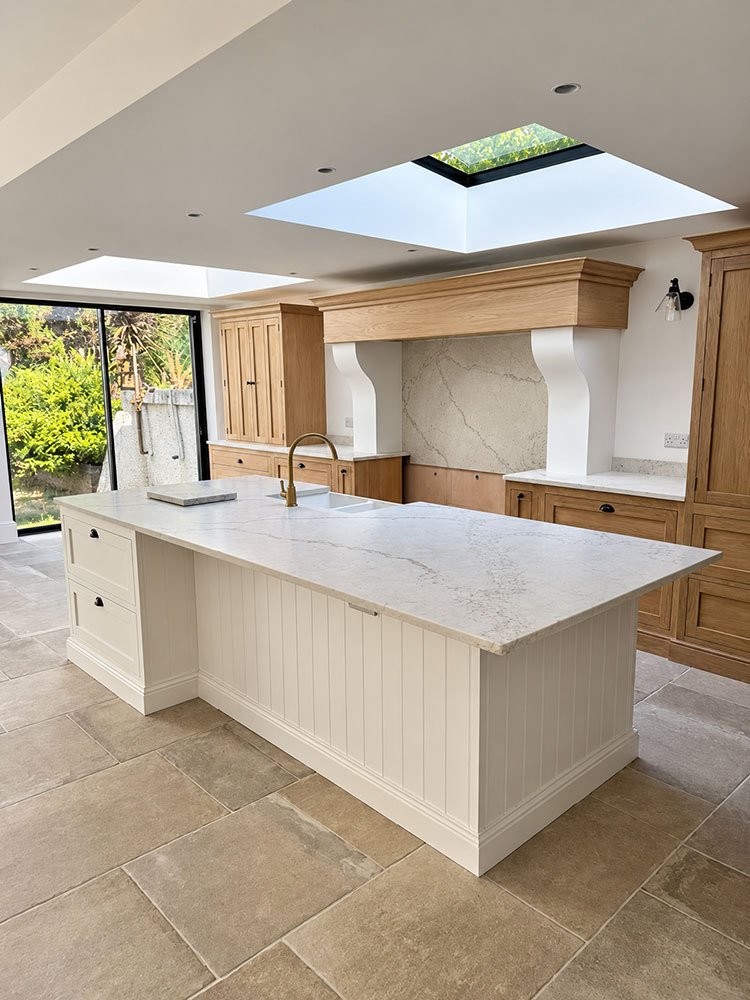 Completed open-plan kitchen at West Drive, Brighton, with large island, oak cabinetry, rooflights and garden glazing