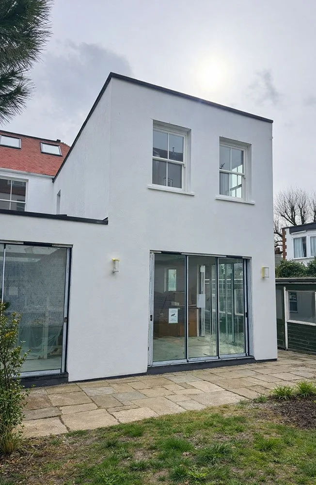 Rear exterior of the house with newly rendered extension and large sliding doors at West Drive, Brighton