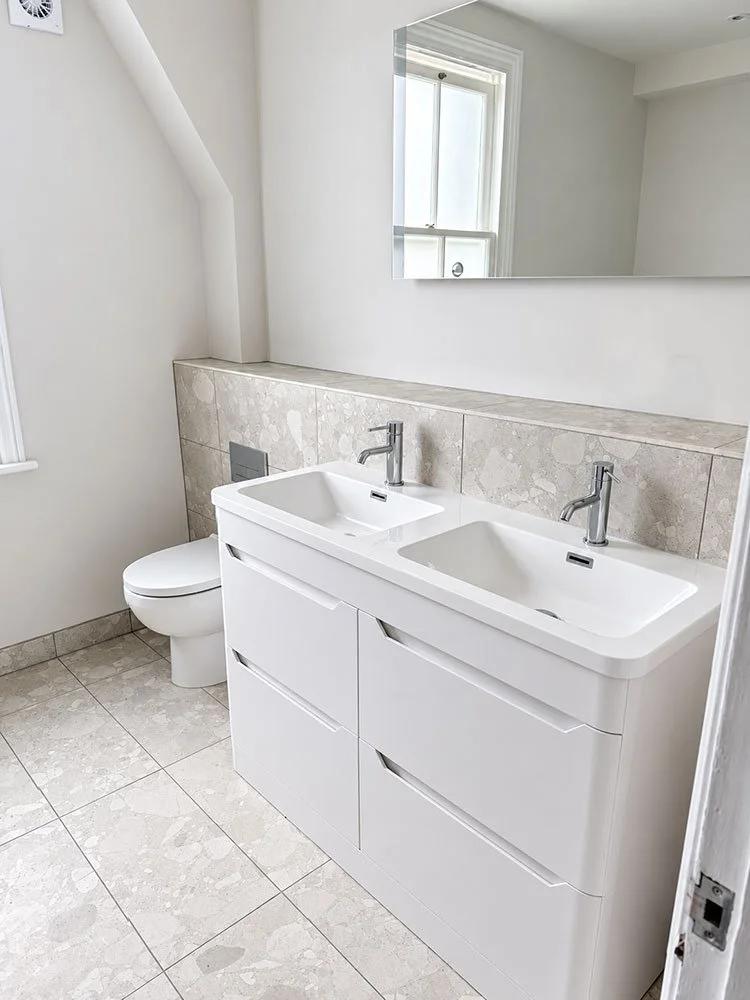 Finished bathroom with double vanity, tiled walls and large mirror at West Drive, Brighton