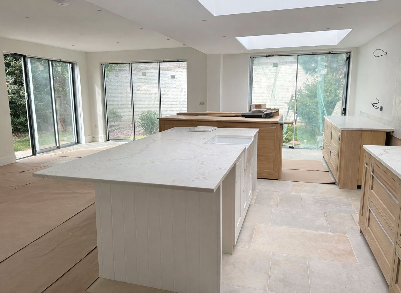 Bright kitchen-dining space with island and garden views through sliding doors at West Drive