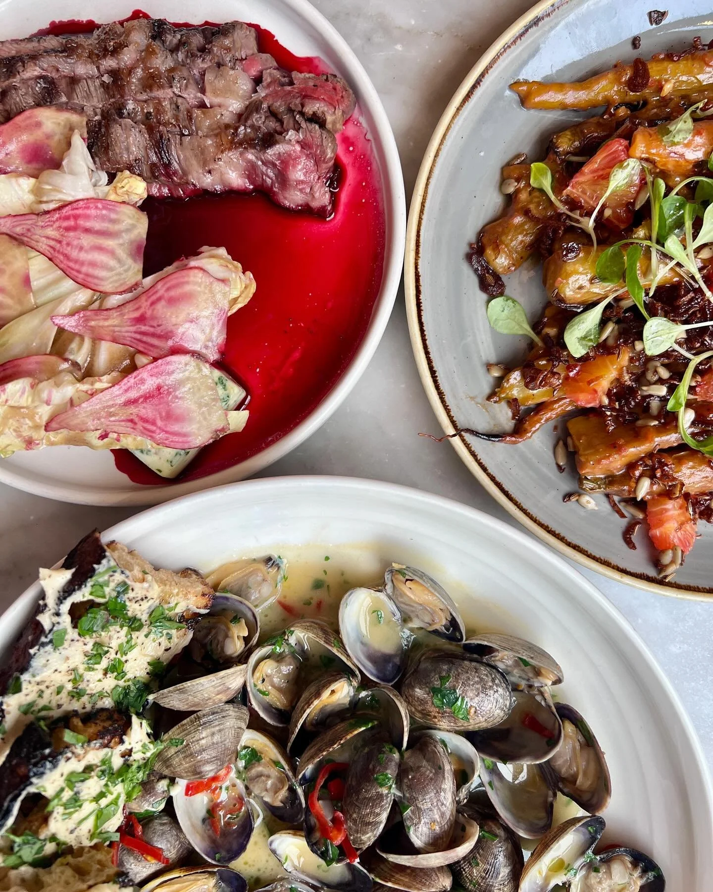 Three plate spread featuring oysters and vegetables SRV Boston