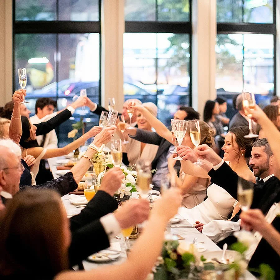 People at a wedding reception toasting with champagne glasses around a decorated table.