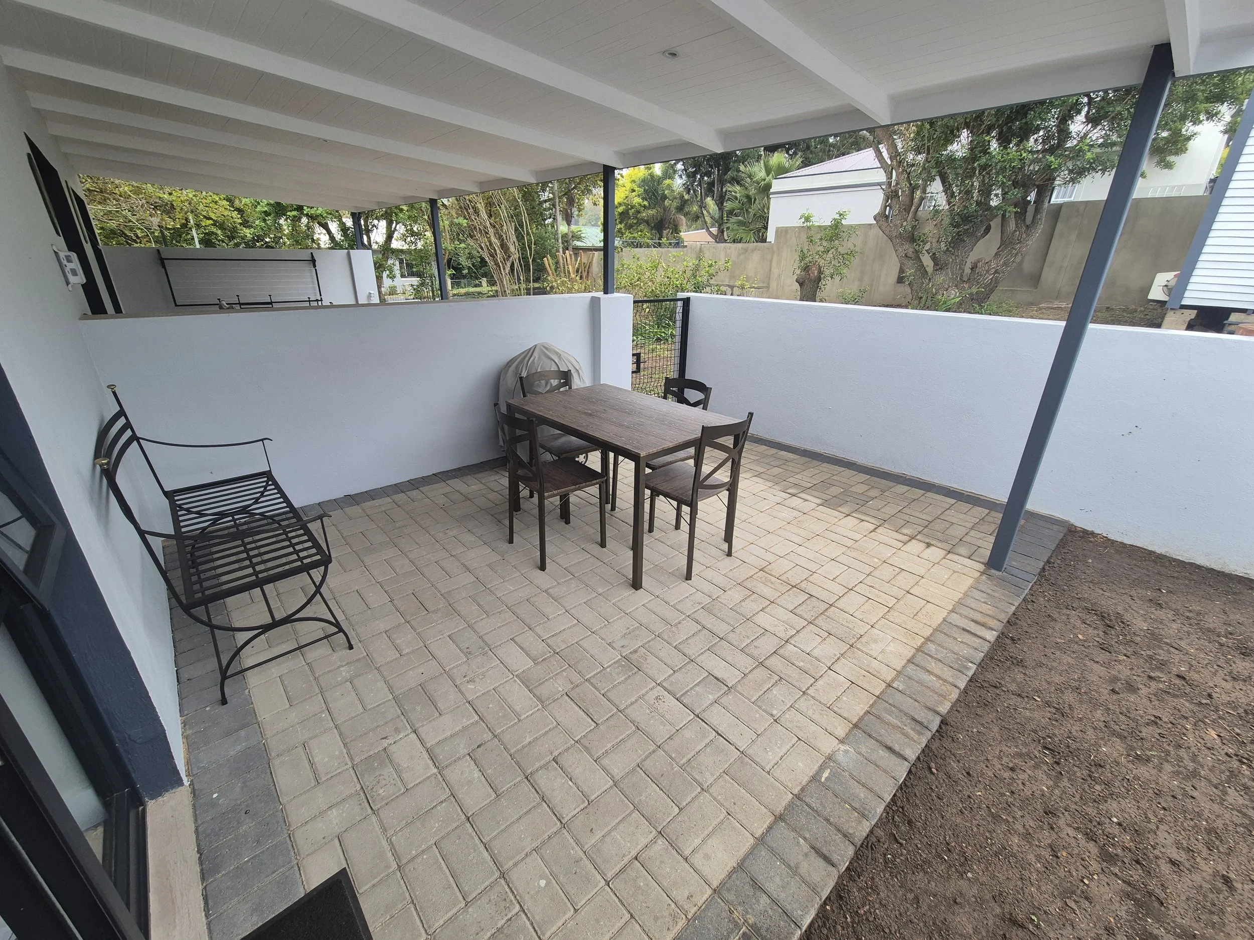 The outdoor seating area has a bench (cushions are kept inside), table and Weber braai. (The grass has grown since this photo was taken)