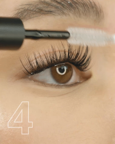 Close-up of a person applying liquid eyeliner to their upper eyelid.