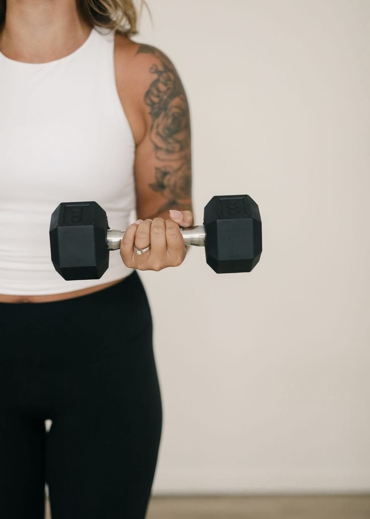 Persona sosteniendo una pesa de mano en un entorno interior.