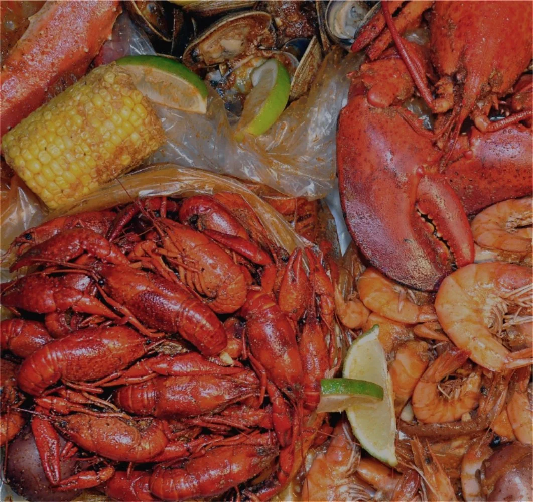 Boiled seafood spread with crawfish, lobster, shrimp, corn, and citrus served on a table.