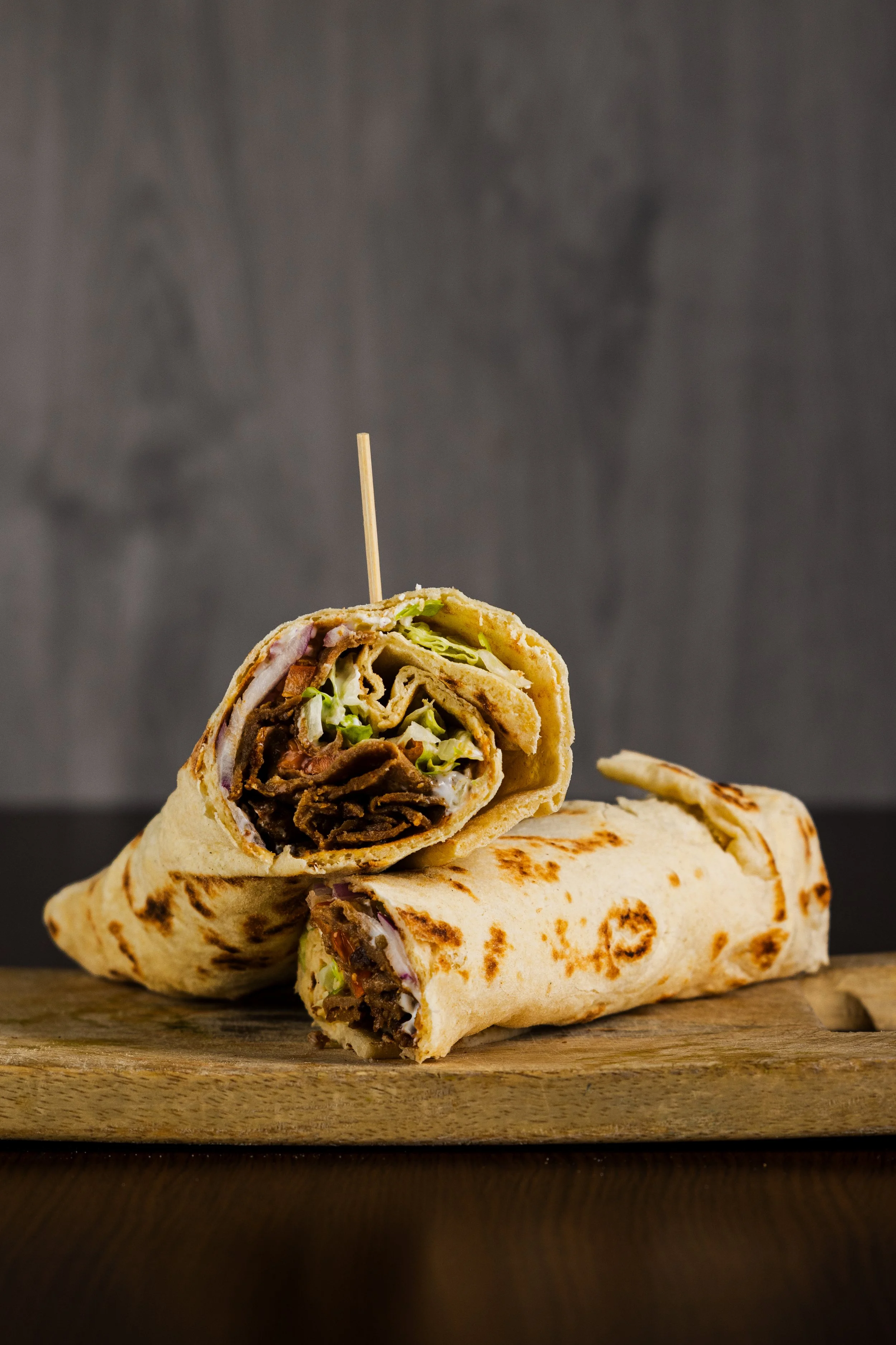 En Dürum med oksekød, salat og grøntsager på træskærebræt.