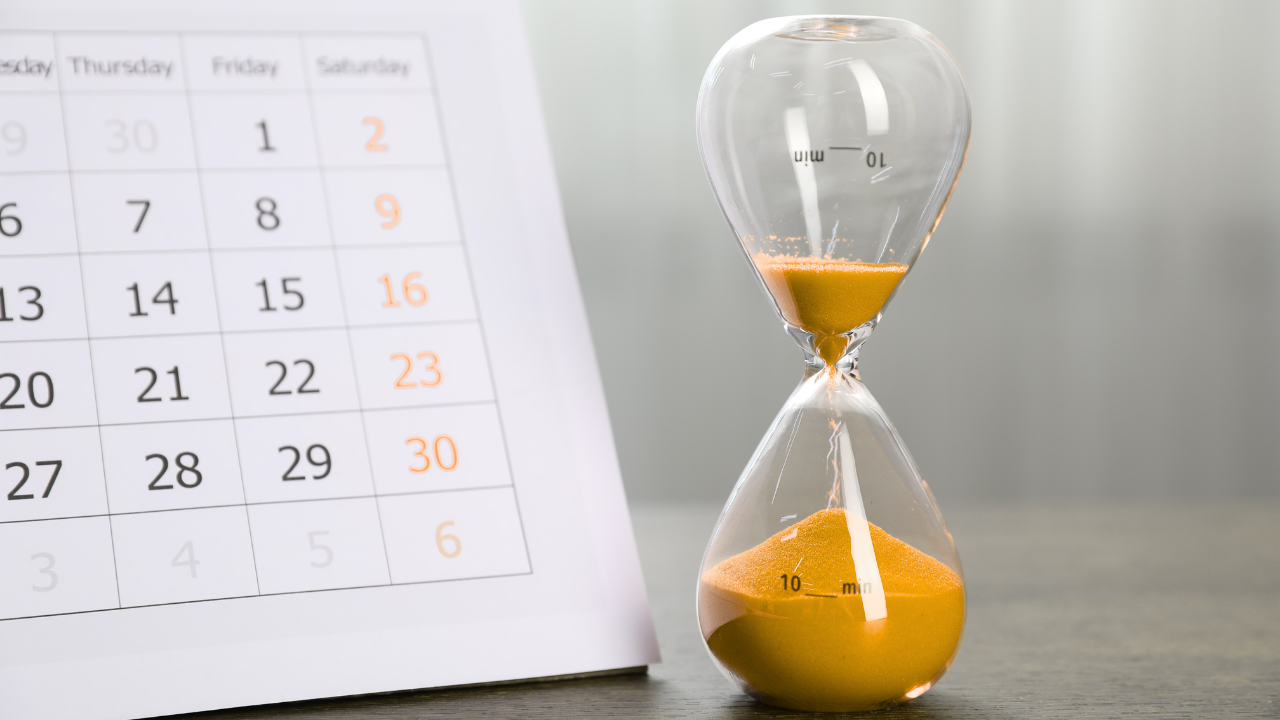 Hourglass and calendar representing pressure from a debt collector threatening a lawsuit without filing one