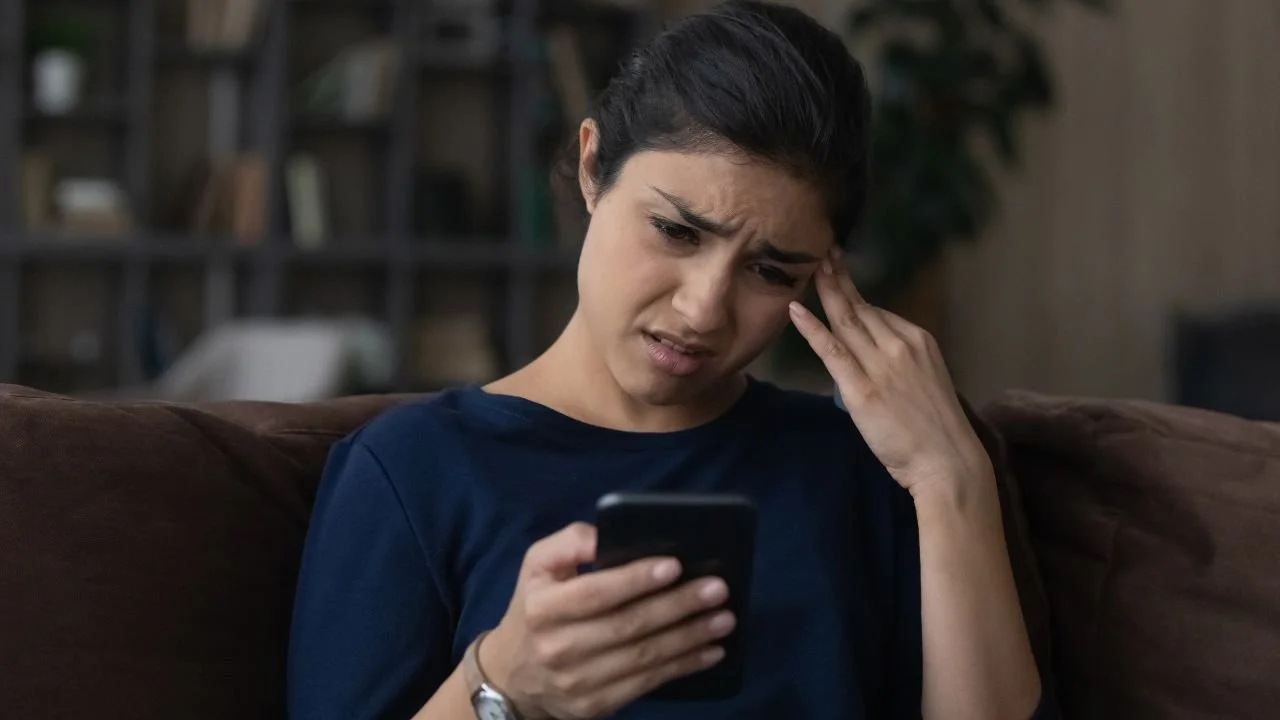Woman looking concerned at phone after contact from Credence Resource Management